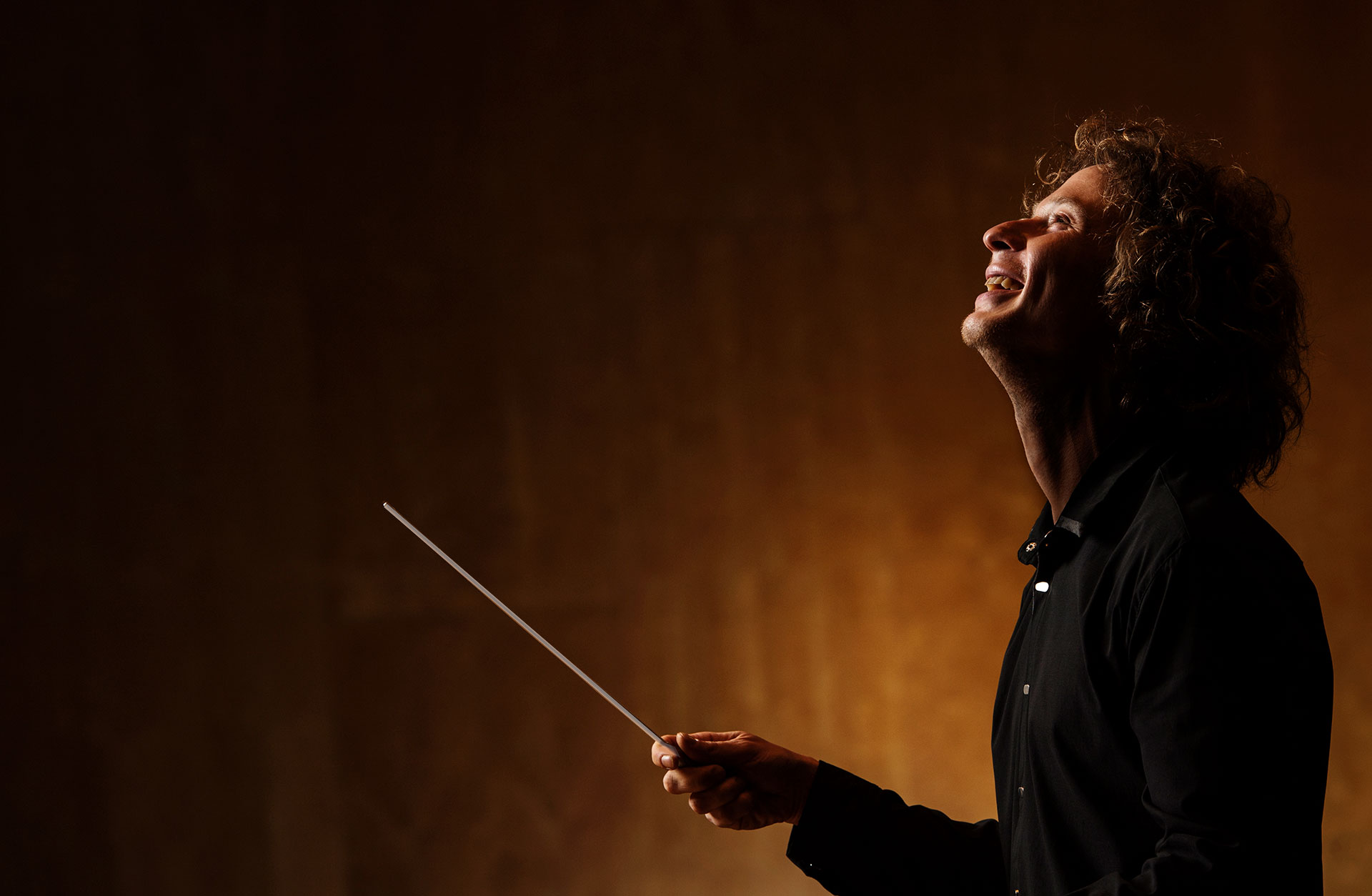 Dirigenten Santtu-Matias Rouvali skrattar med taktpinne handen.