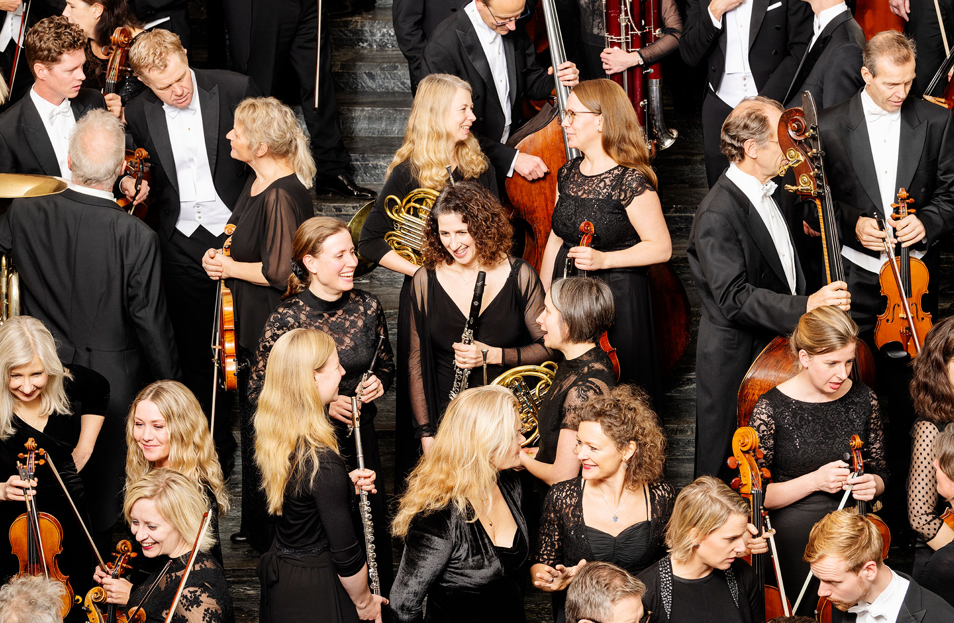 Musiker ur Göteborgs Symfoniker minglar med instrumenten i handen.