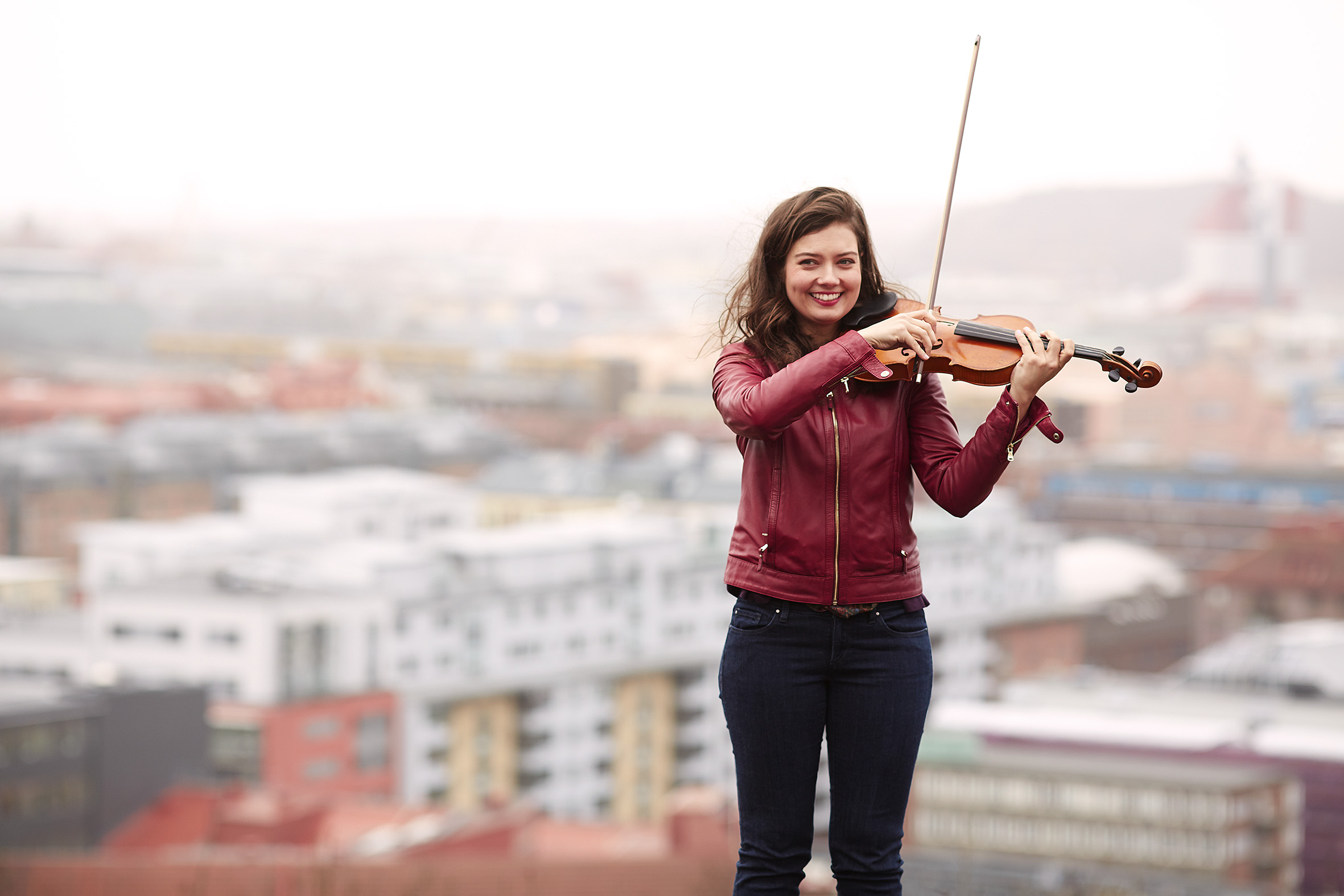 Justyna Jara från Göteborgs Symfoniker spelar violin på hustak med utsikt över hus i bakgrunden.