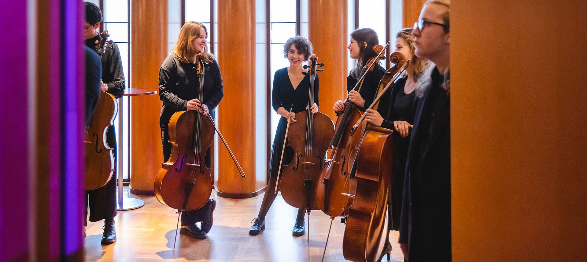 Glada ungdomar med cello i konserthusets foajé.