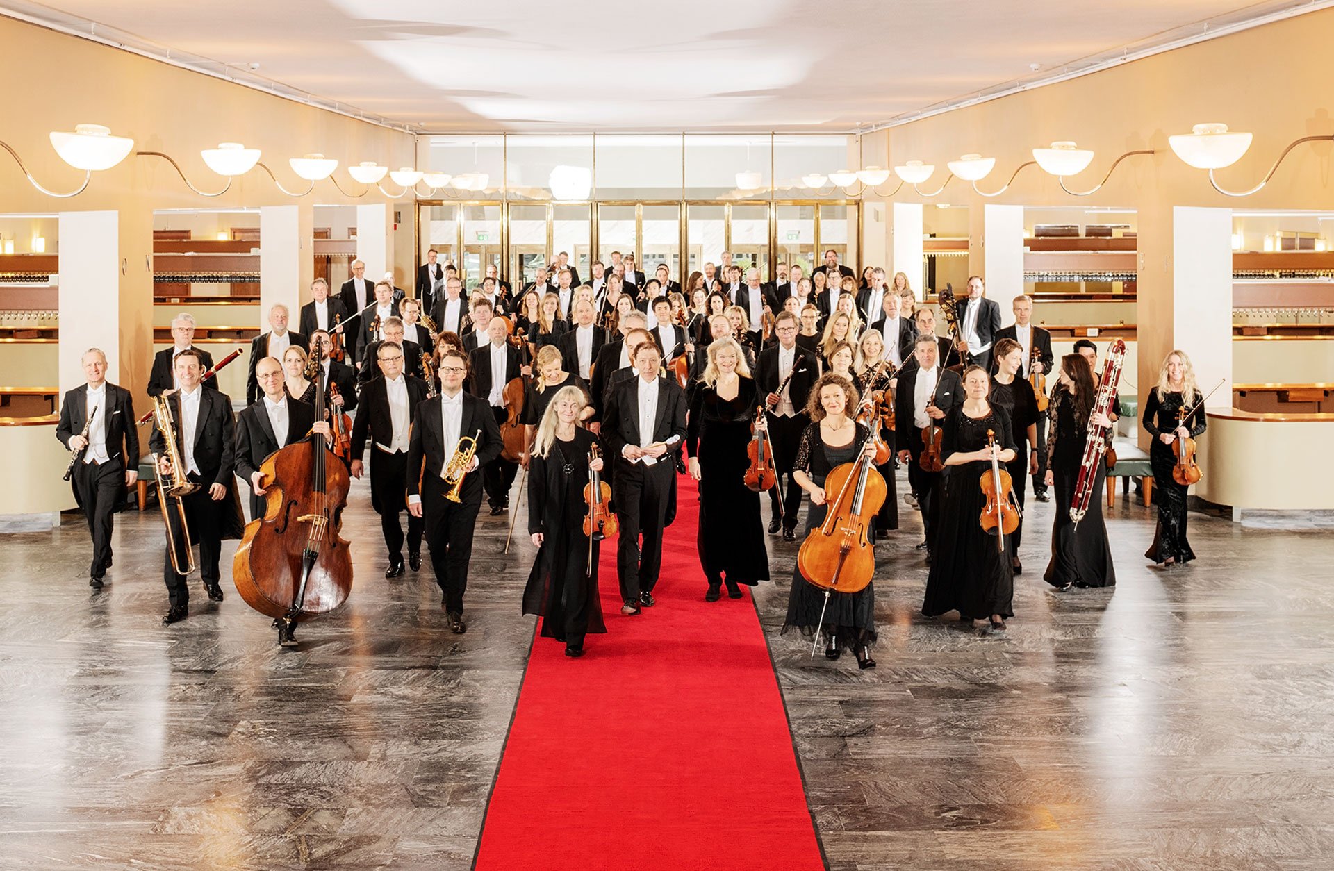 Orkesterns musiker går mot kameran med instrumenten i handen.