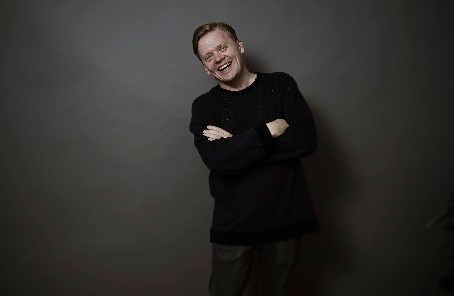 Dirigenten Pekka Kussisto lutar sig skrattande mot en vägg.