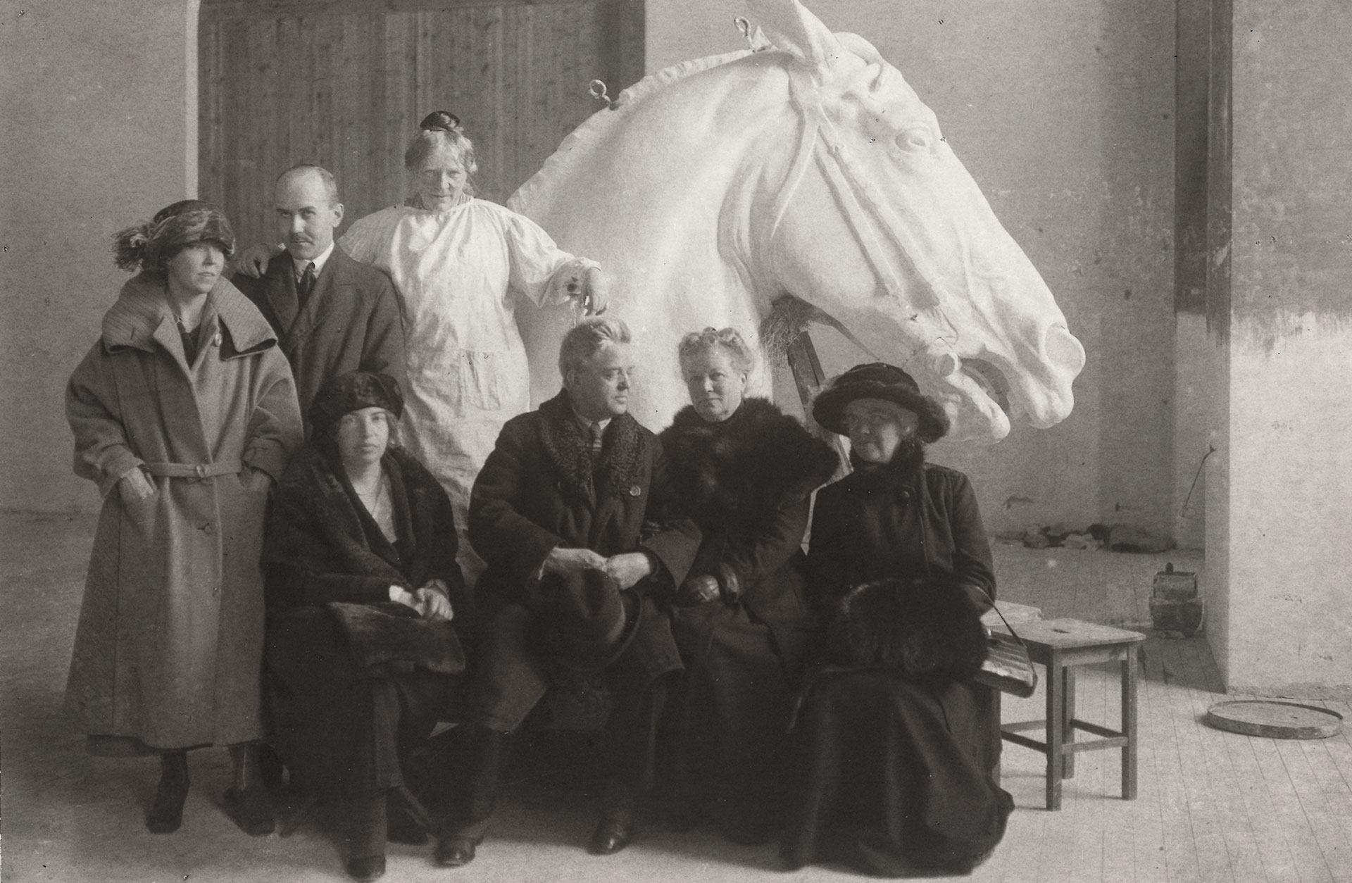Gruppbild med medlemmar ur familjerna Mannheimer och Nielsen framför ett stort skulpterat hästhuvud.