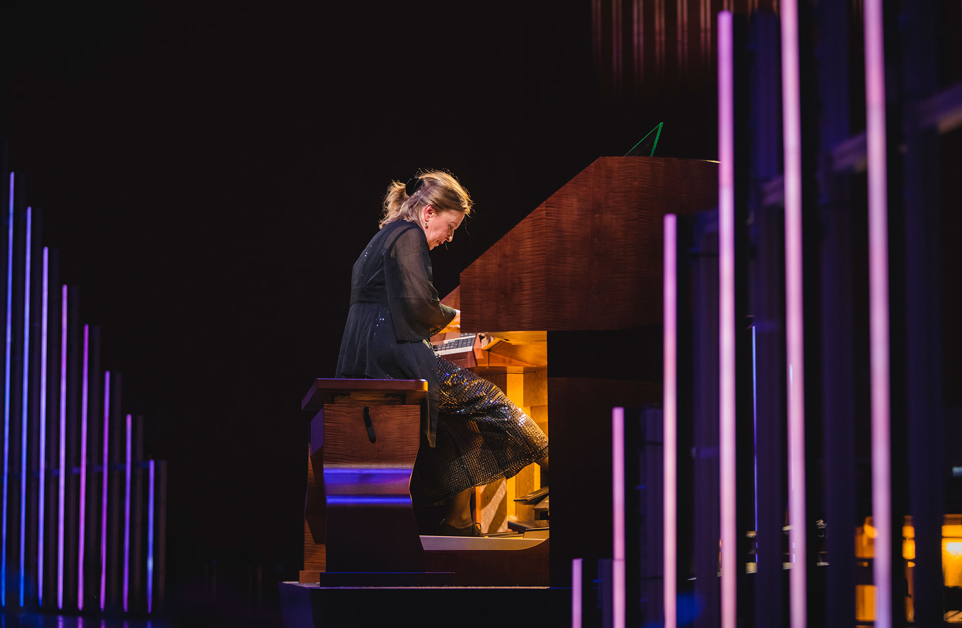 Organisten Karin Nelson i intensiv pose vid orgelns spelbord.