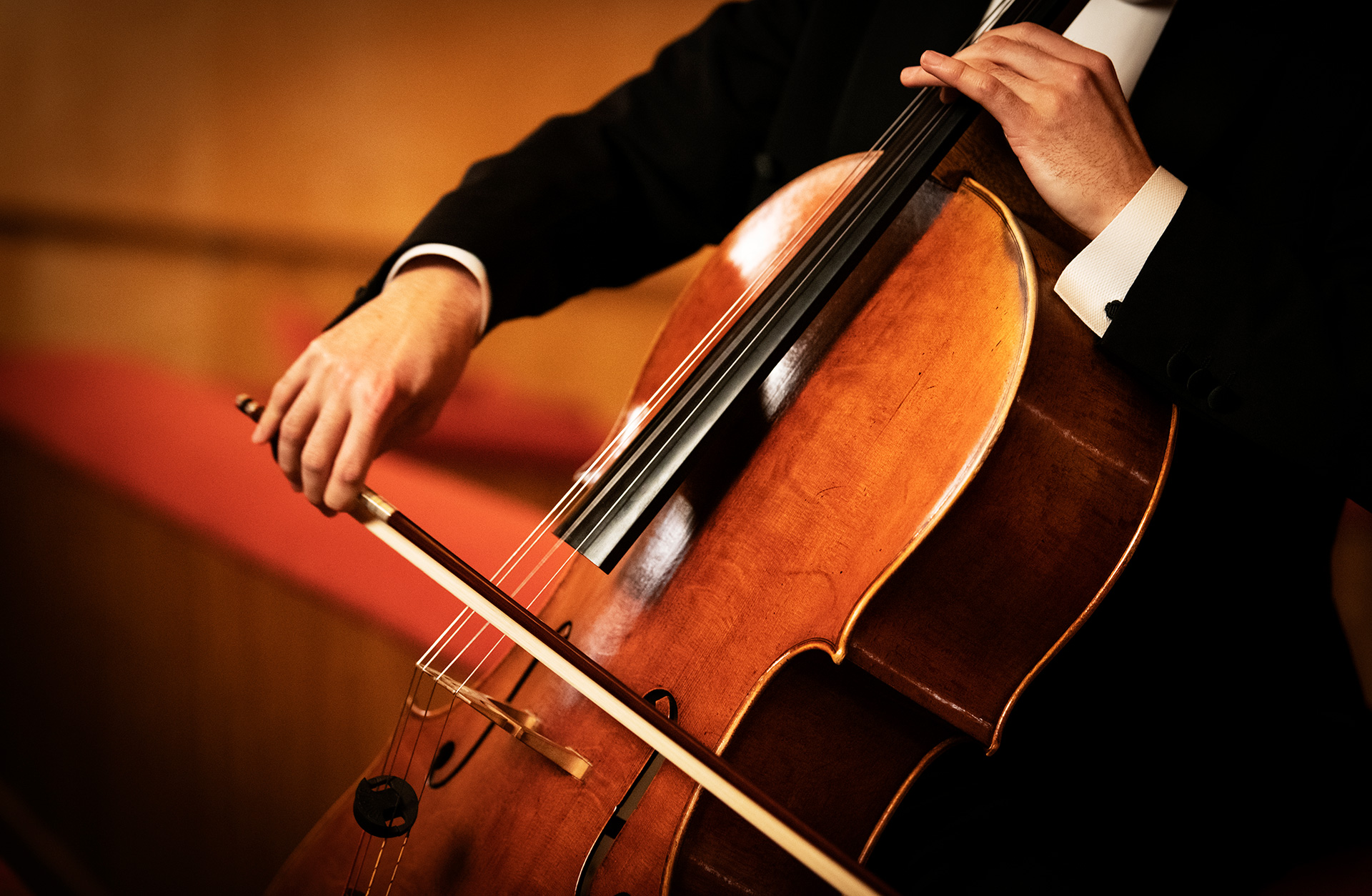 Hand som håller i en stråke som spelar på en cello
