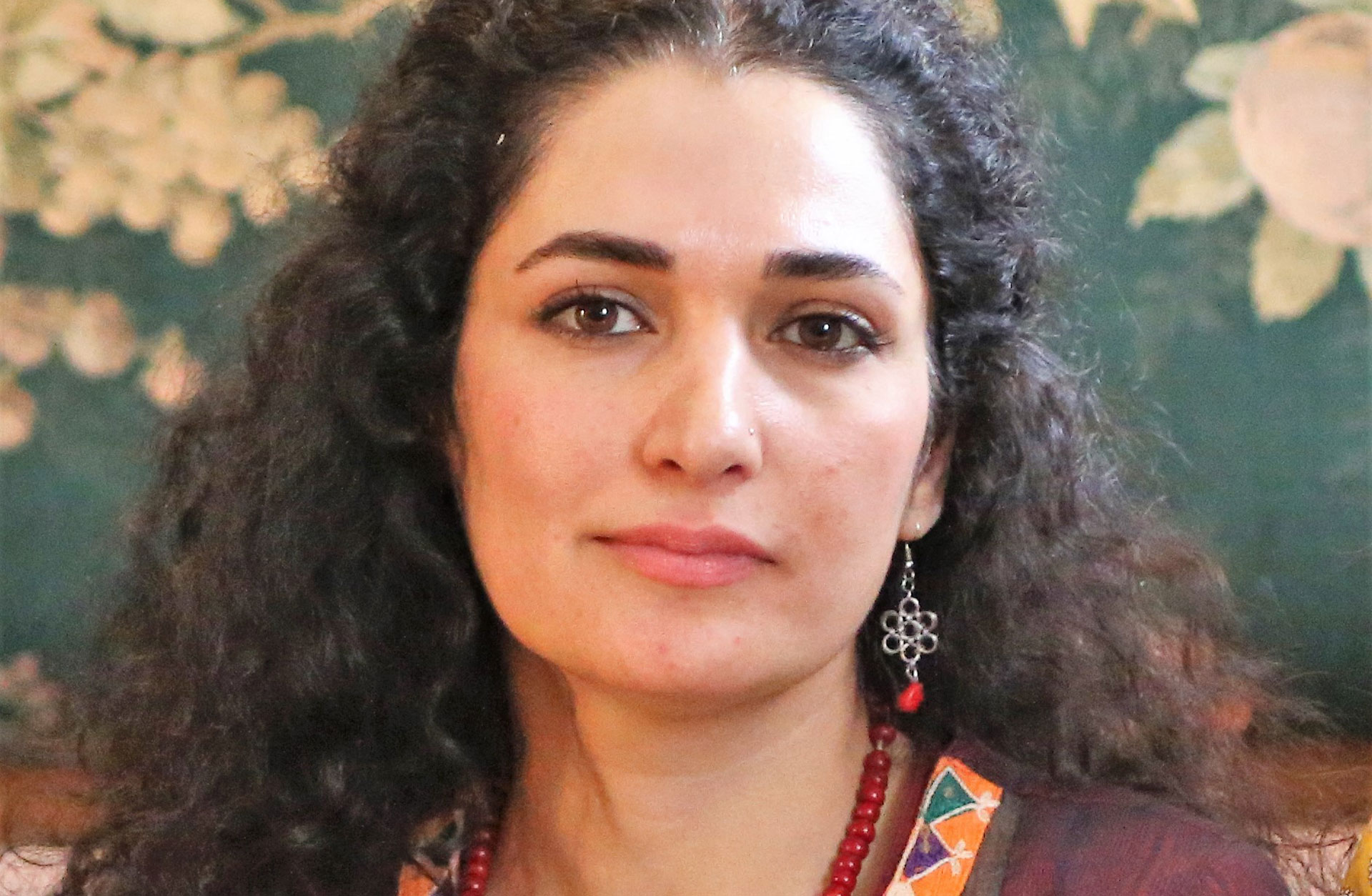 Ansiktsporträtt av Maryam Javidmehr. Hon har mörkt långt lockigt hår och bruna ögon.