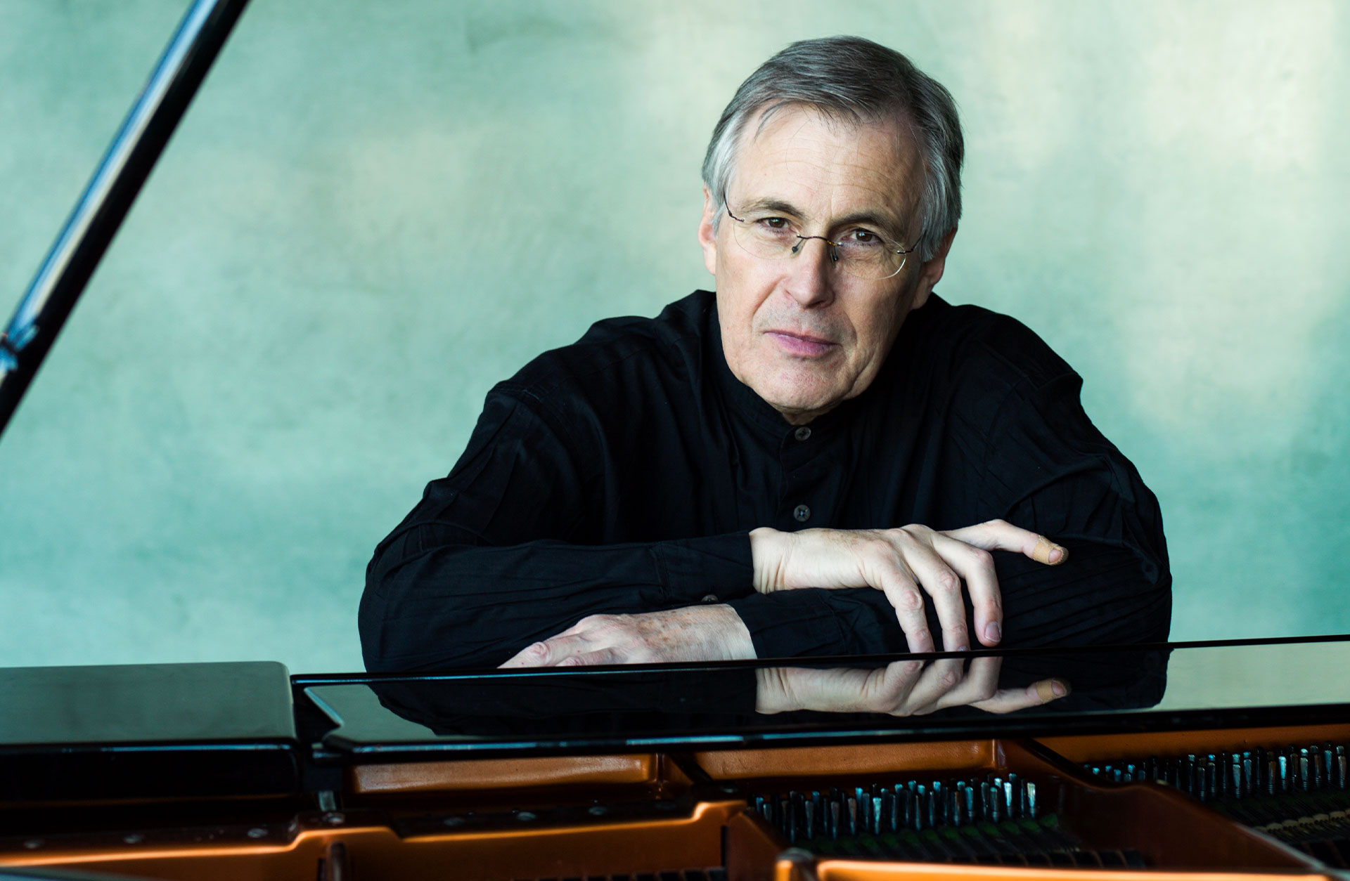 Christian Zacharias tittar in i kameran. Han sitter vid pianot.