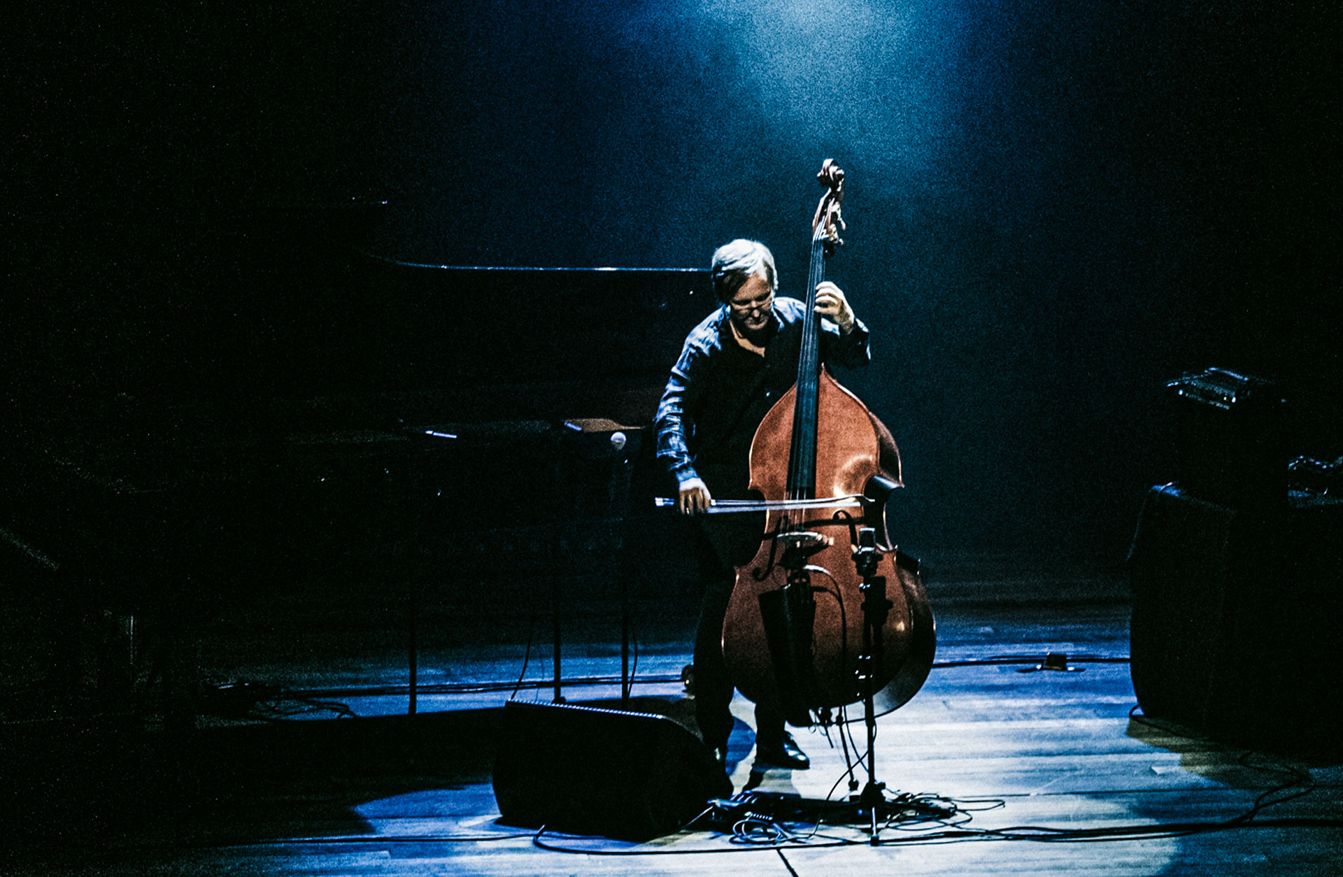 En man med kontrabas på scenen i spotlight.