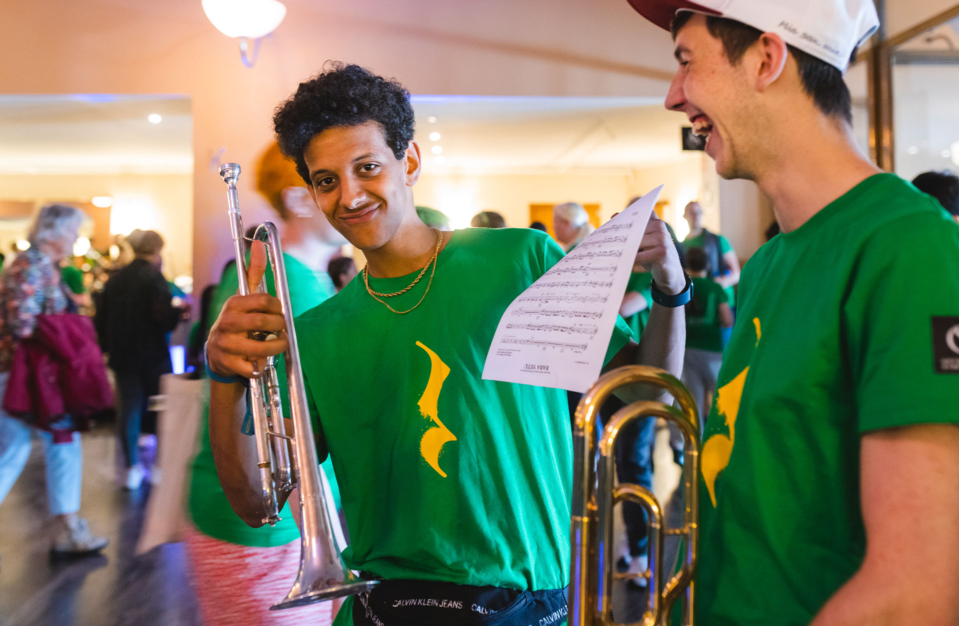 Två glada killar poserar framför kameran. Den ena håller upp sin trumpet och den andra skrattar med sin trombone i handen.