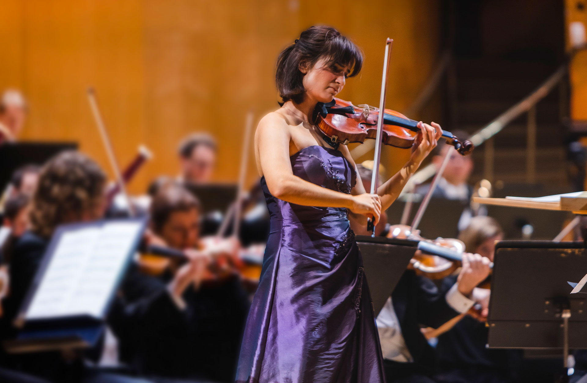 Ava Bahari spelar violin i lila klänning framför orkestern