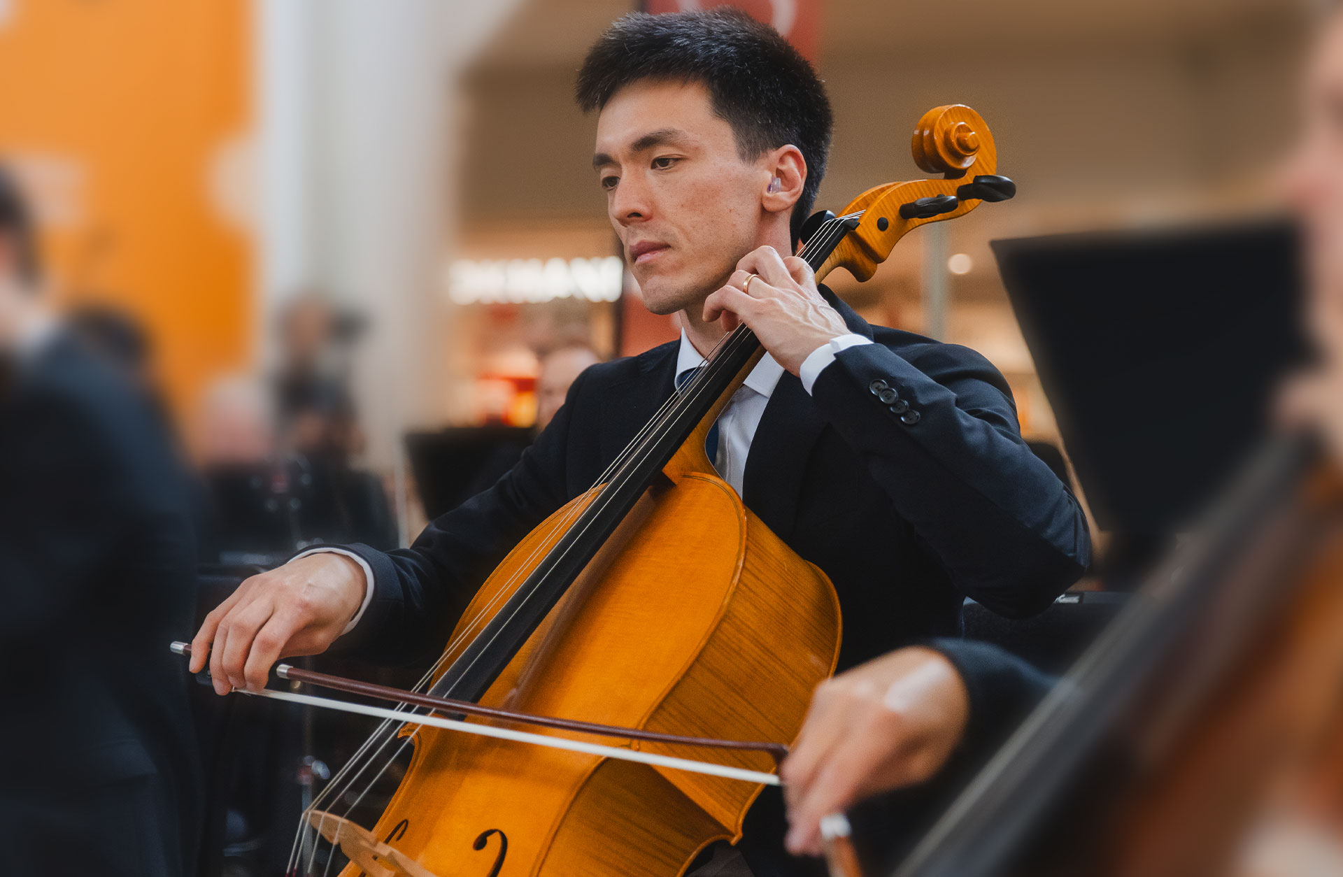 En cellist sitter och spelar med blicken fäst i noterna.
