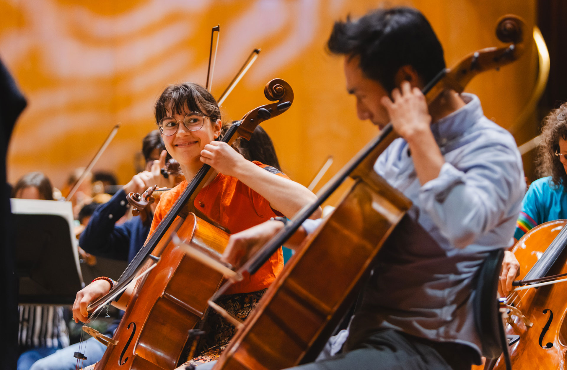 Ung cellist spelar och tittar med glad blick på den äldre musikern vid hennes sida.