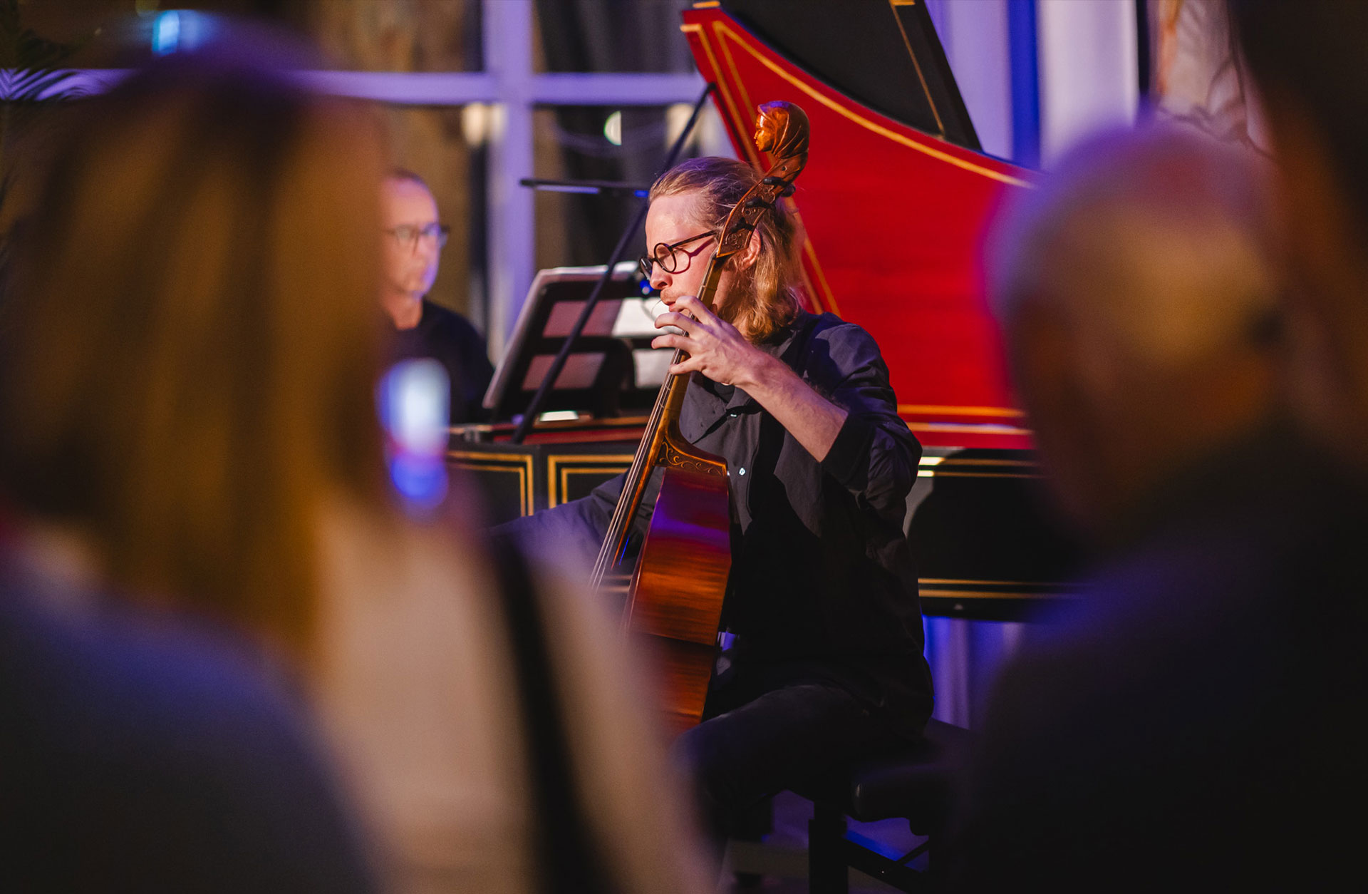 Cellist spelar på scenen, man skymtar publik framför honom.