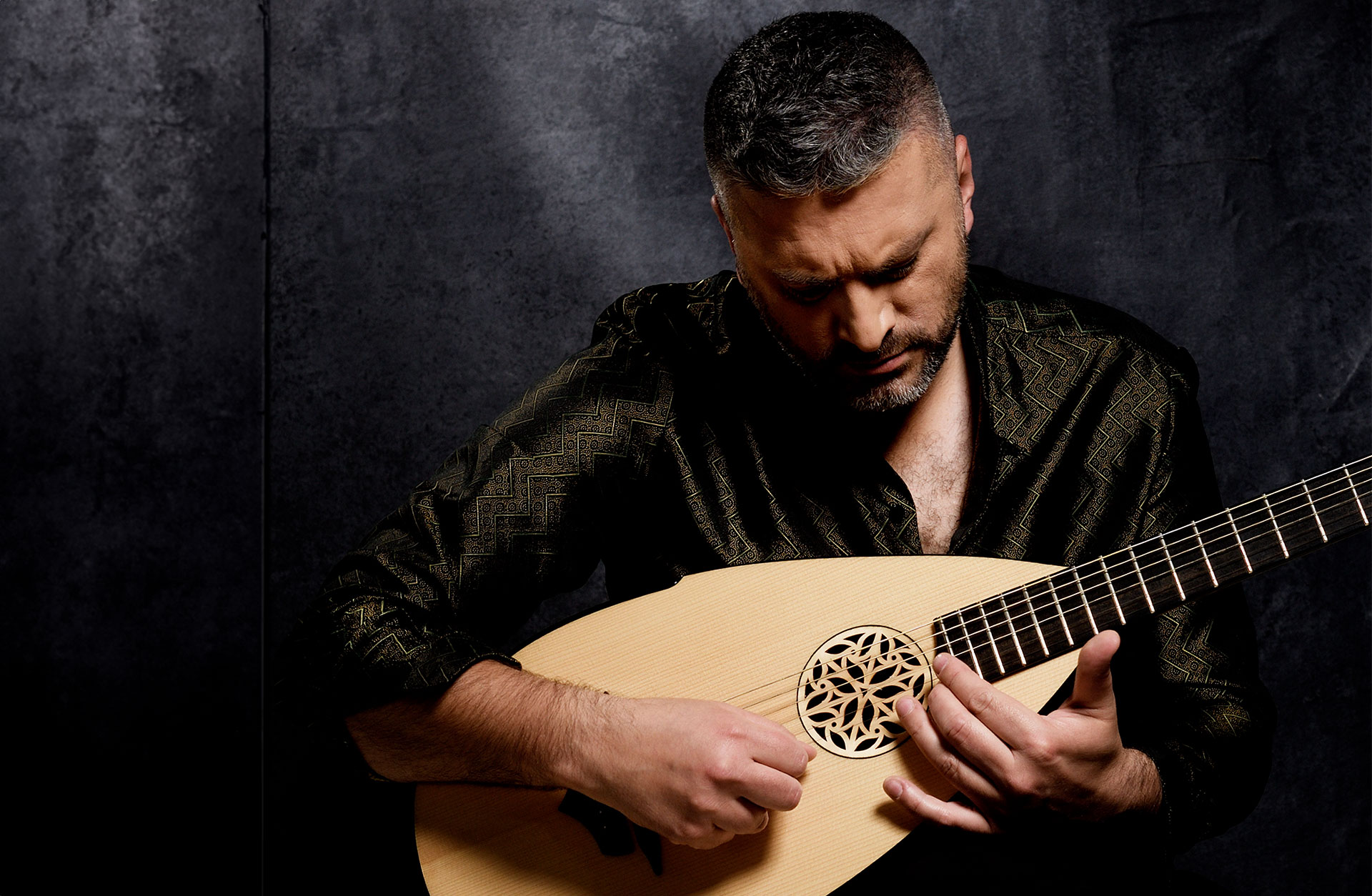 En man sitter med en luta i famnen och spelar.