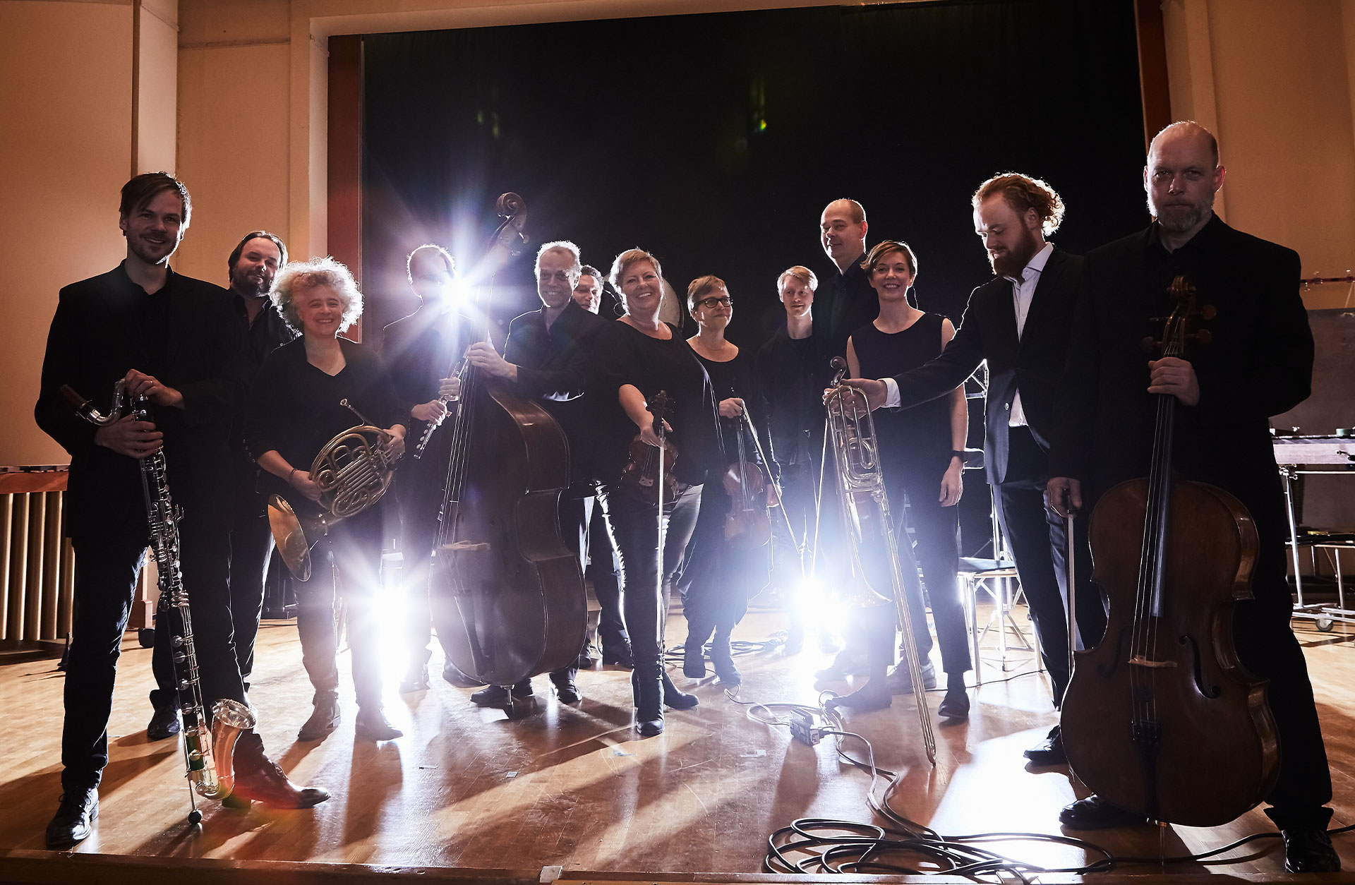 Ensamble står på rad framför kameran och lampor skapar motljuseffekt i bilden.