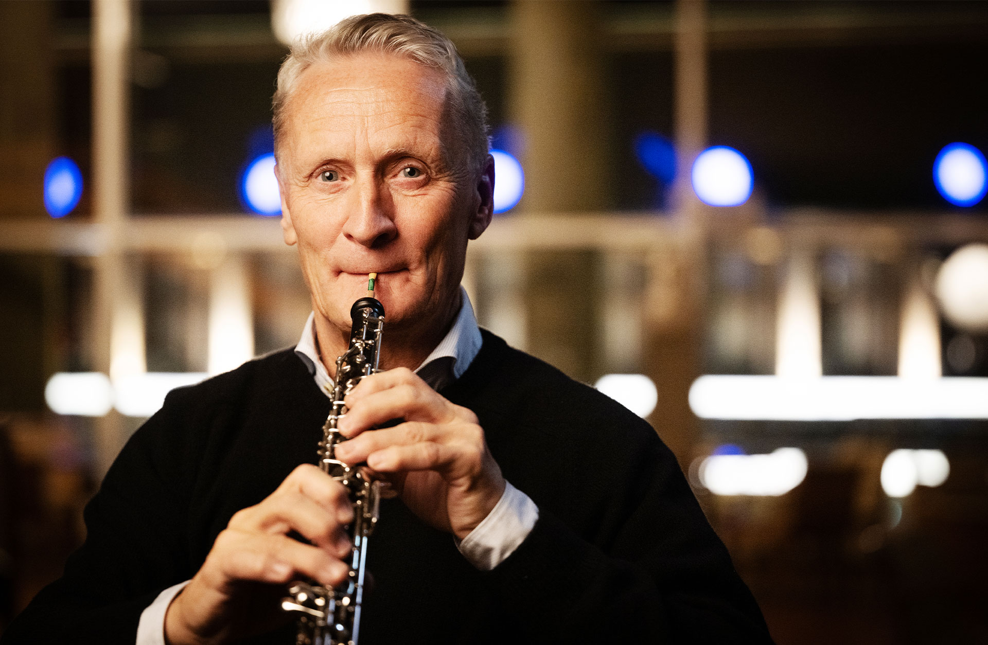 Mårten Larsson, en kortklippt man i 60-årsåldern tittar in i kameran och spelar på sin oboe.