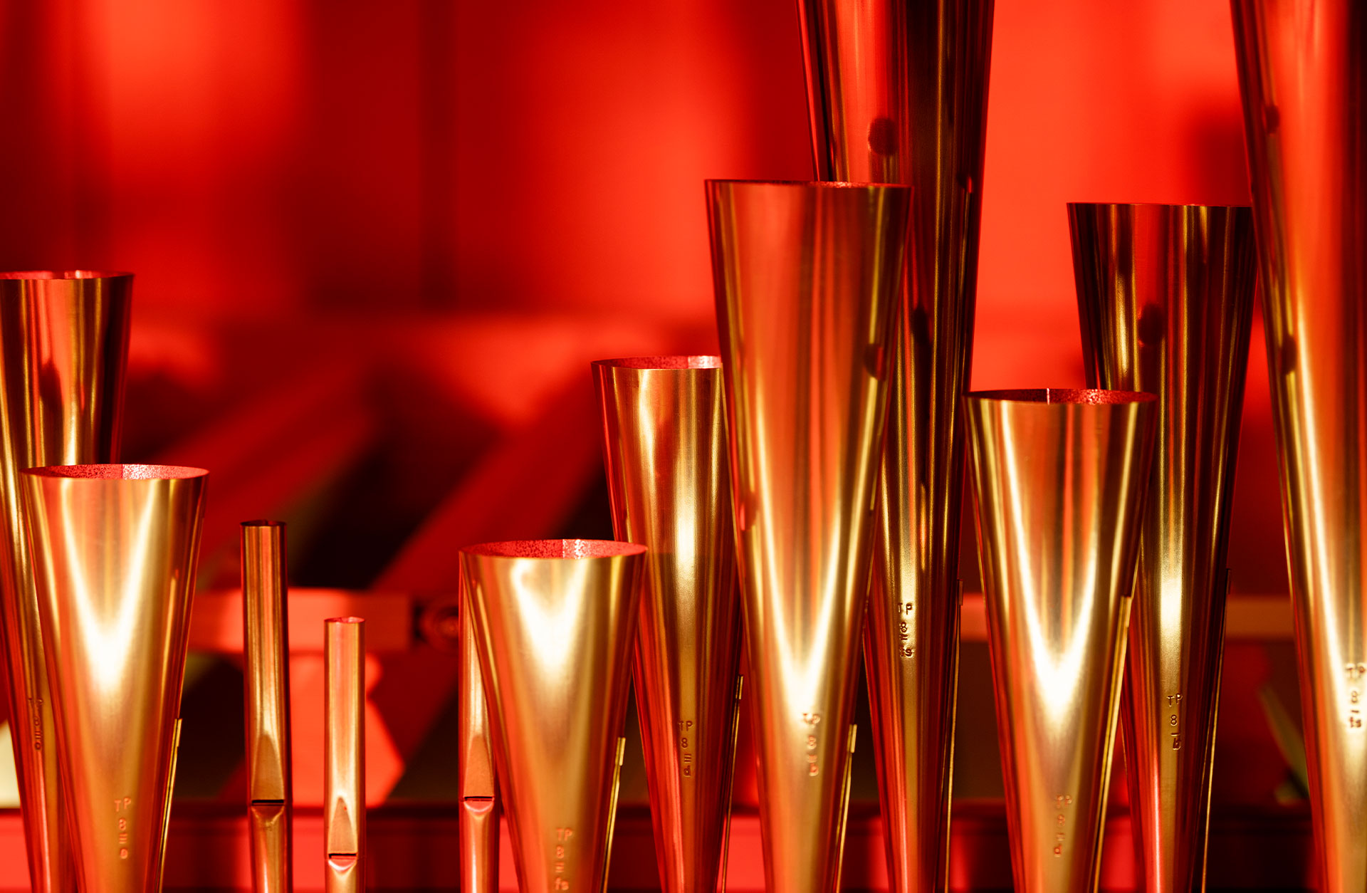 Närbild på orgelpipor i guldig nyans mot rödfärgad bakgrund