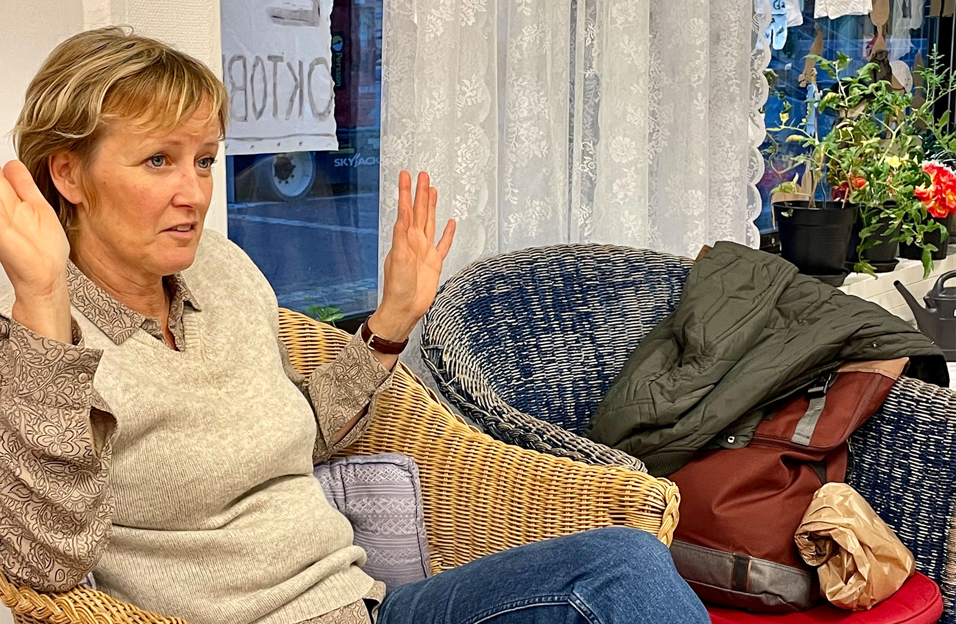 Helena Fornegård sitter i en korgstol. Hon pratar och gestikulerar med händerna.