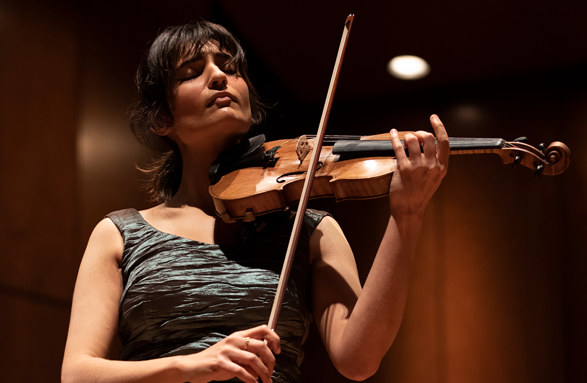 Ava Bahar spelar violin. Hon är klädd i klänning och blundar.