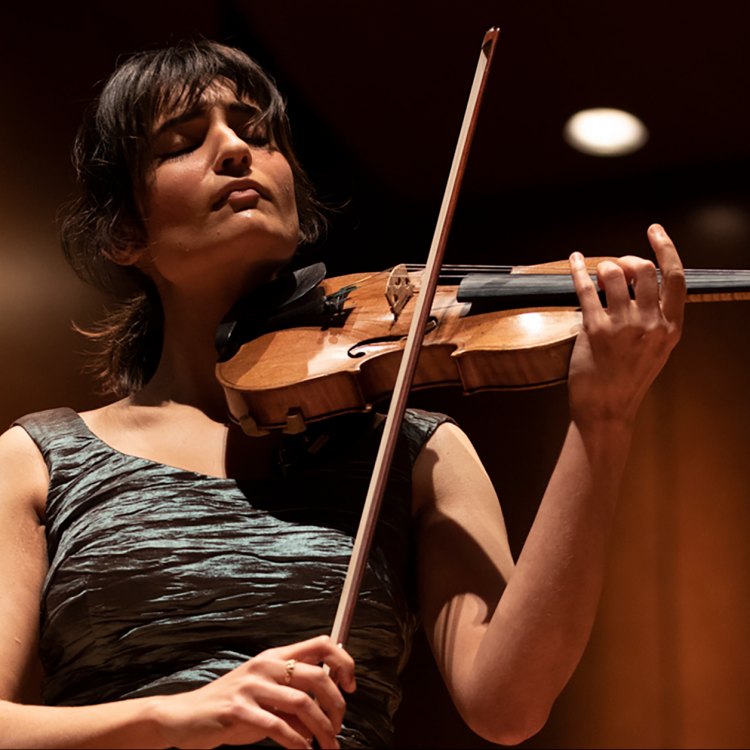 Ava Bahar spelar violin. Hon är klädd i klänning och blundar.
