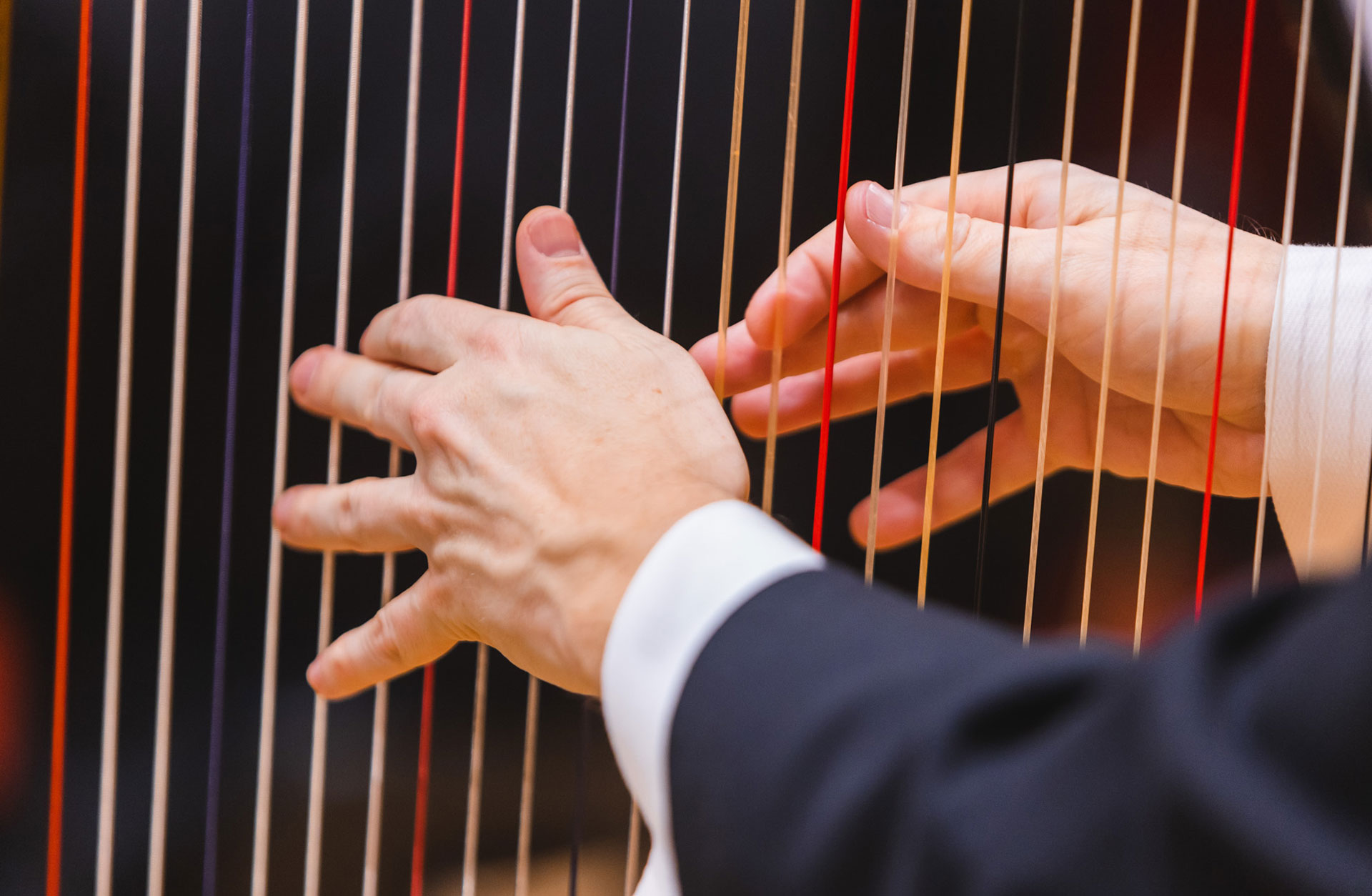 Händer spelar på harpsträngar.