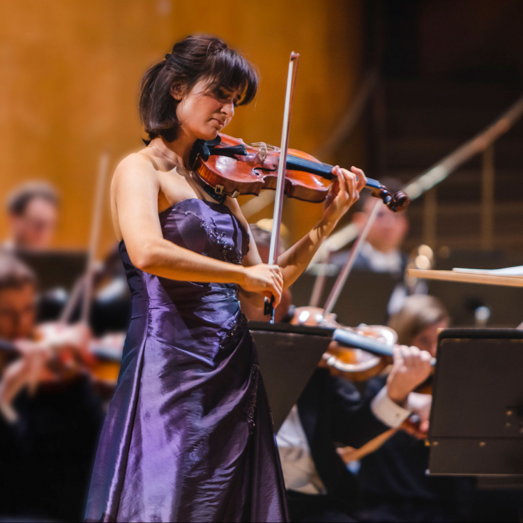 Ava Bahari spelar violin i lila klänning framför orkestern