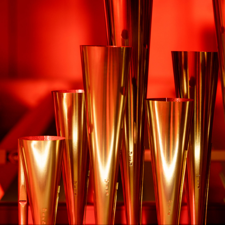 Närbild på orgelpipor i guldig nyans mot rödfärgad bakgrund