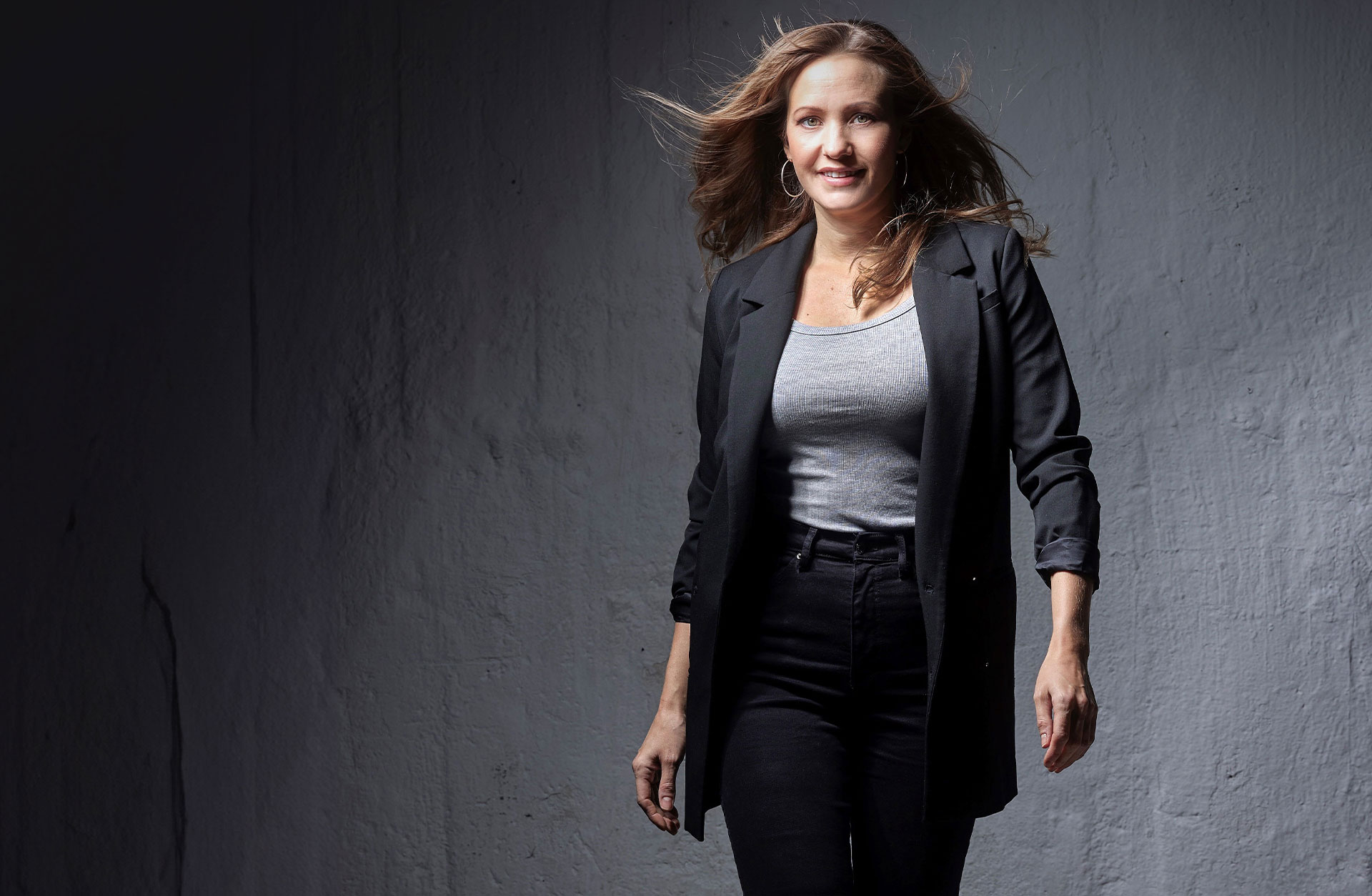 Hanna Husáhr går mot kameran med fläkt i sitt långa blonda hår. Hon är glad.