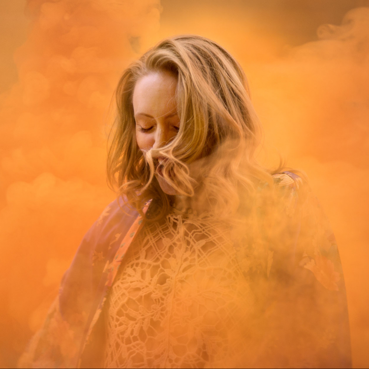 Kvinna i organefärgad rökridå.