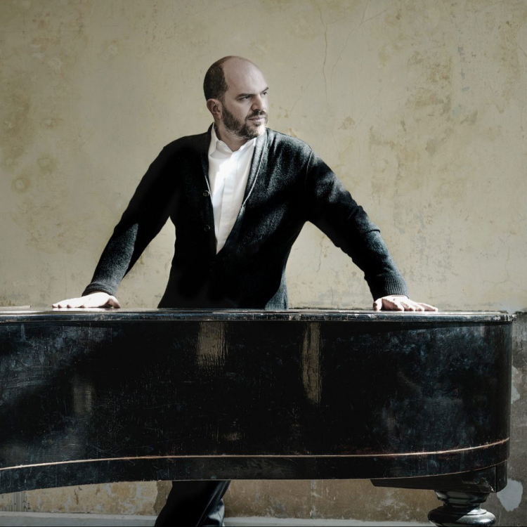 en man står vid sin flygel och blickar åt höger - mot ljuset