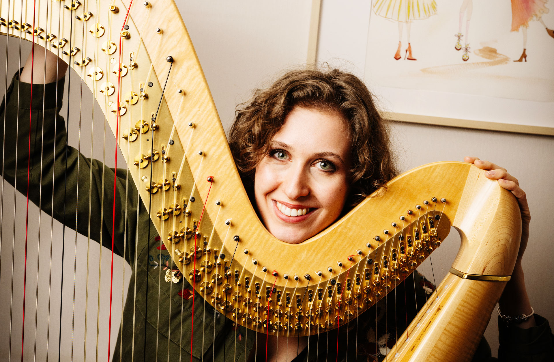 en glad Clara Garde skrattar mot kameran vid sin harpa.
