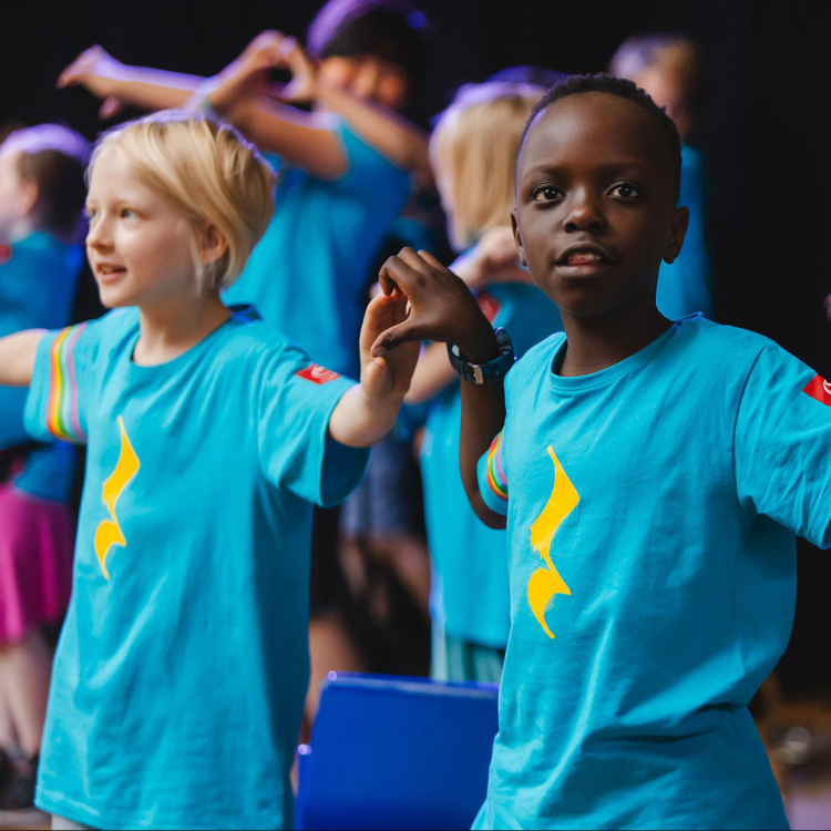 Barn på rad som håller hand med tröjor från musiklägret Side by Side.