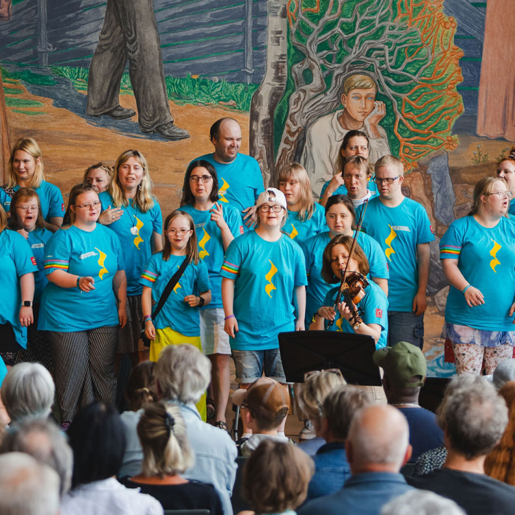 Körsångare tillsammans med en gitarrist och en violinist.