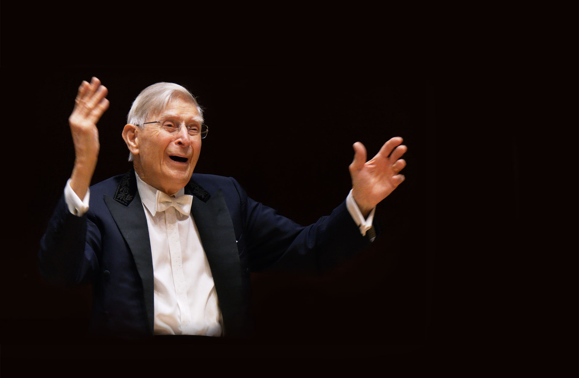 dirigenten Herbert Blomstedt står med armarna i luften och ler