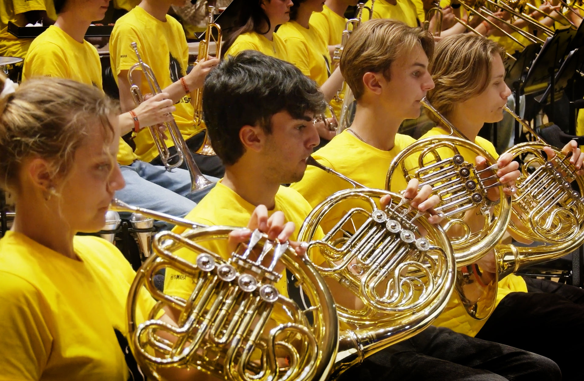 Flera musiker med instrument i gula tröjor.