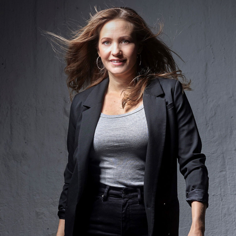 Hanna Husáhr går mot kameran med fläkt i sitt långa blonda hår. Hon är glad.