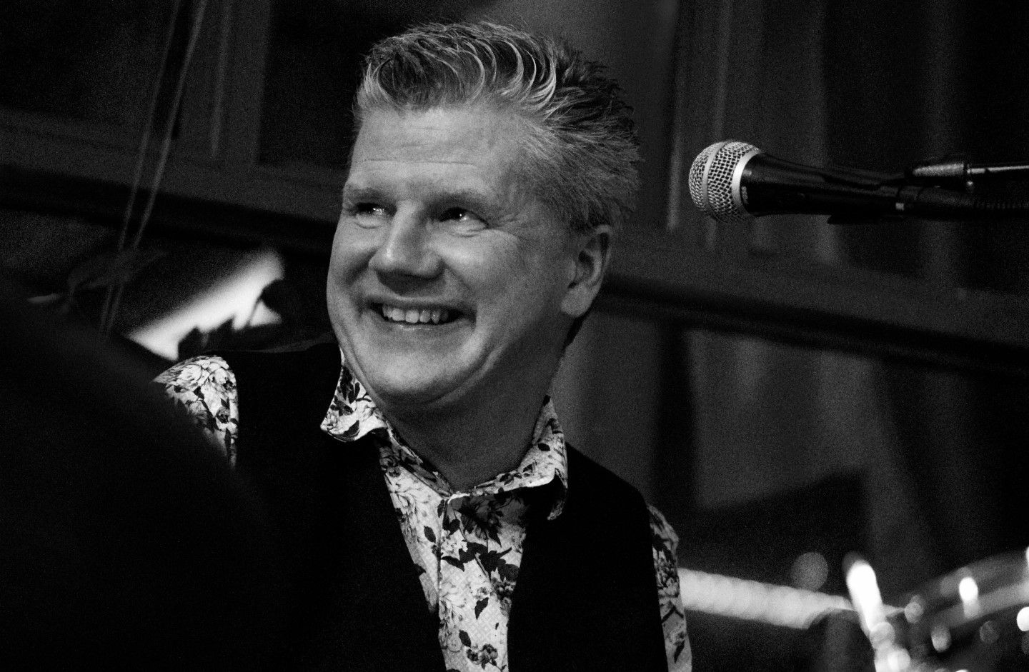 Svartvit bild på en man som ler och kollar bort från kameran.