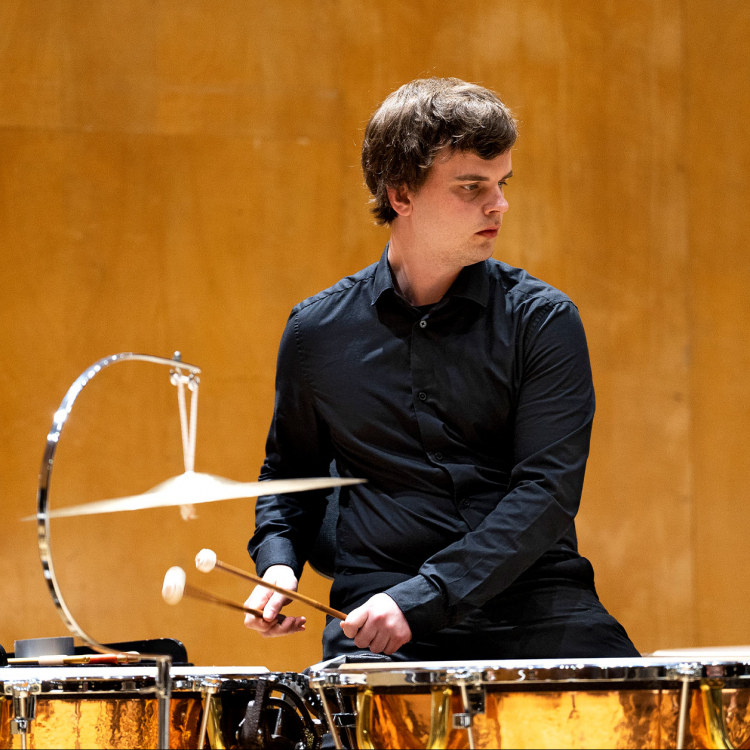 En ung man sitter vid två pukor och slår