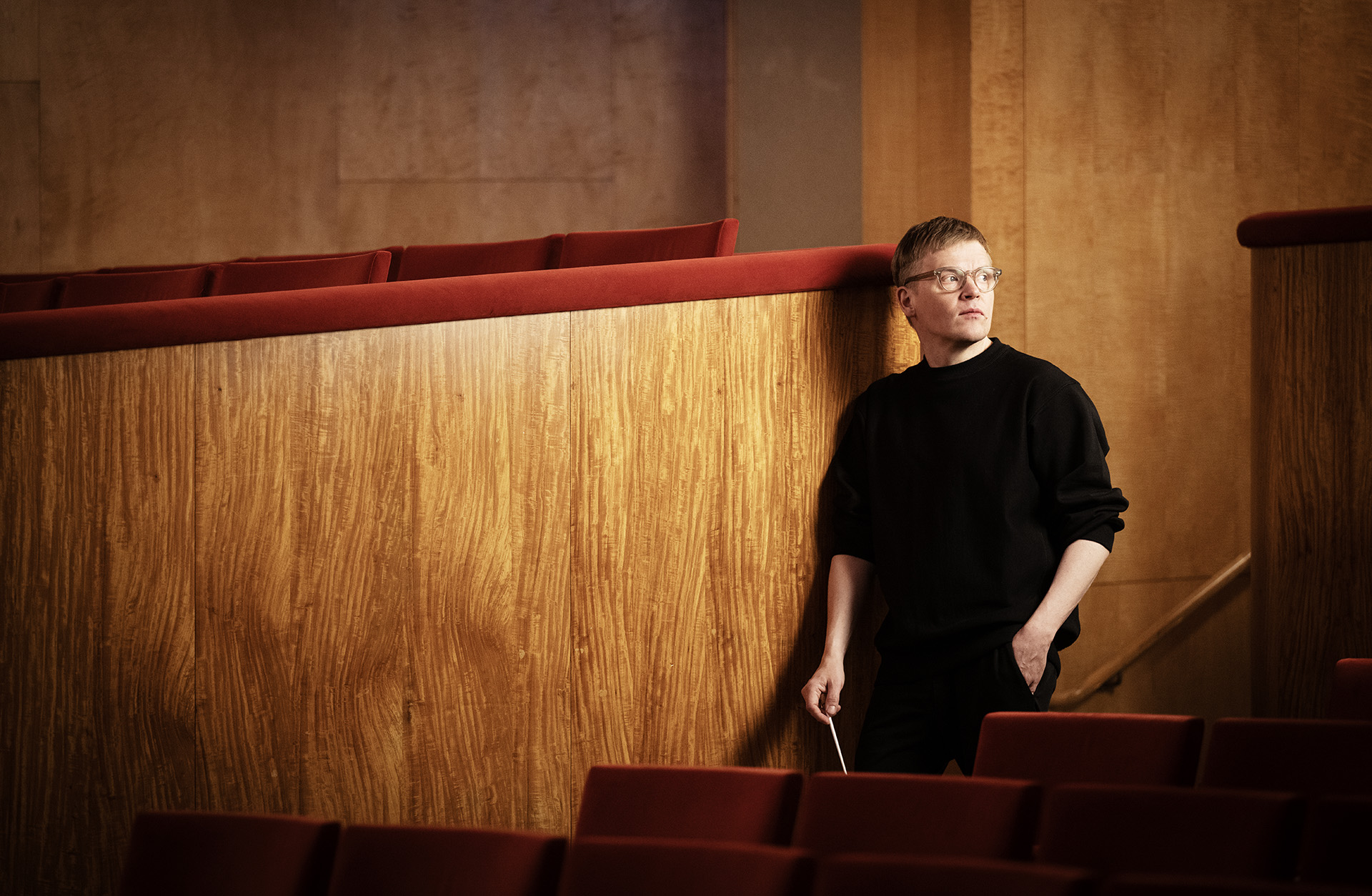 Pekka Kuusisto står lutan mot en vägg i trä