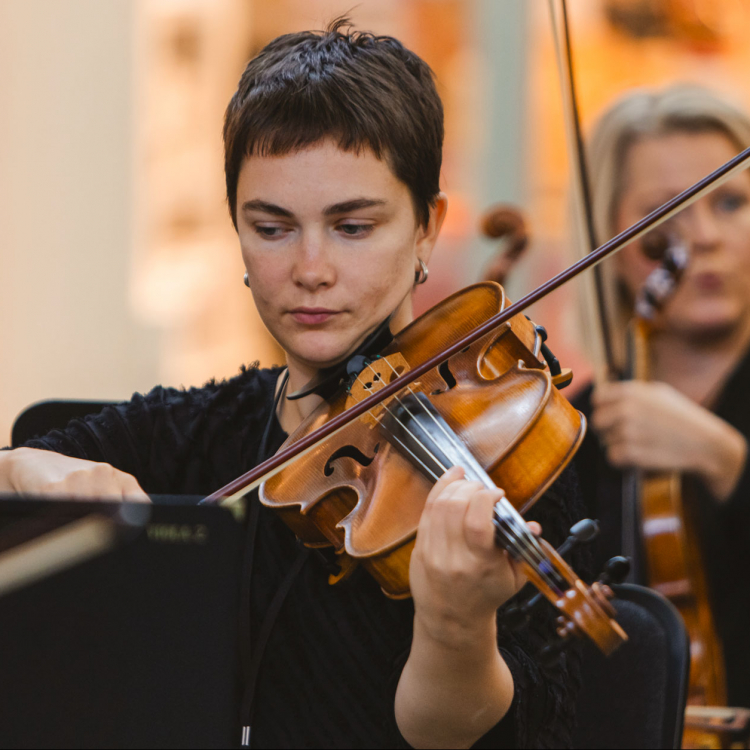 En ung kortklippt kvinna spelar violin.