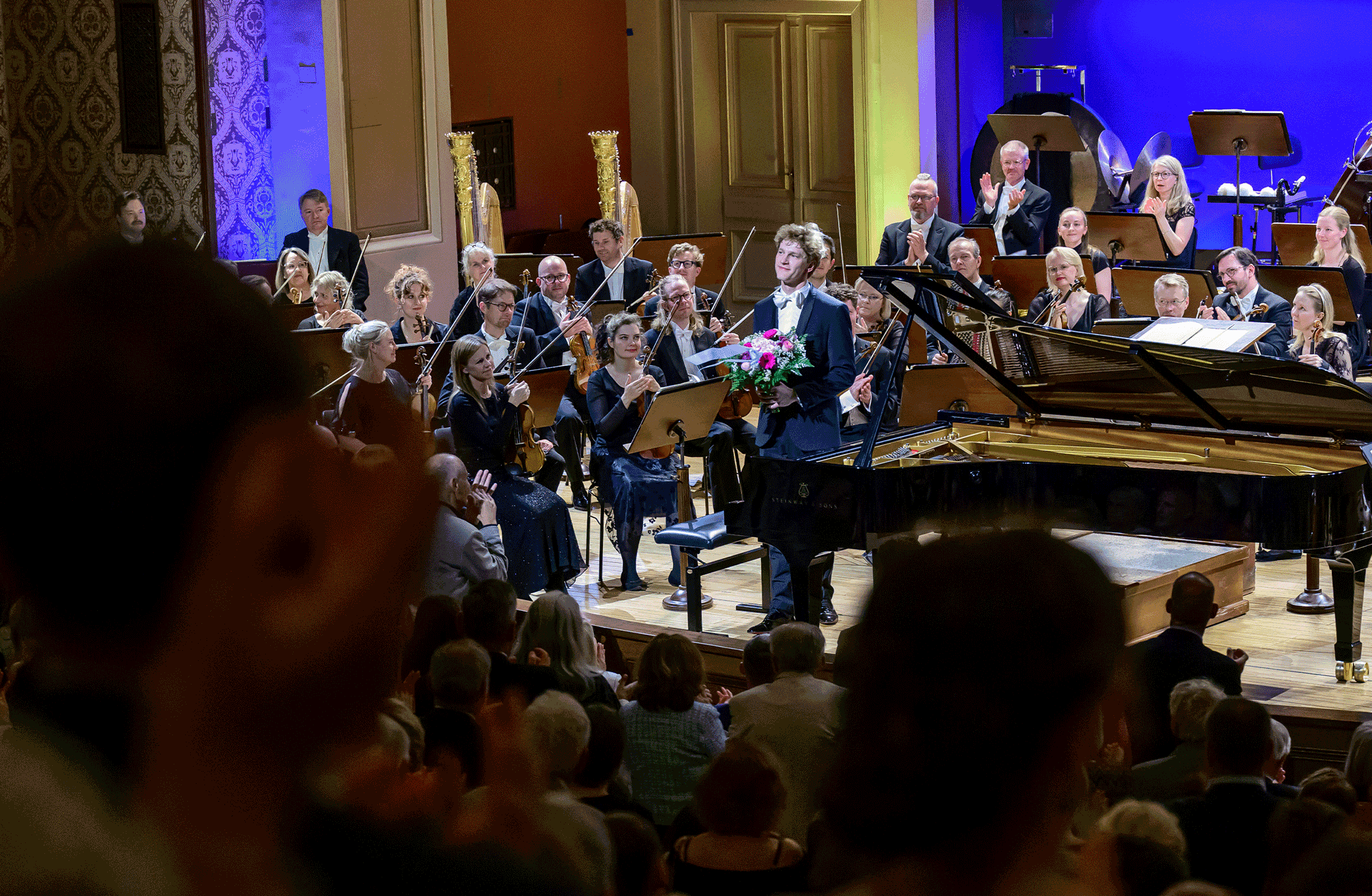 Jan Lisiecki står framför flygeln med en bukett blommor och tackar för applåderna.