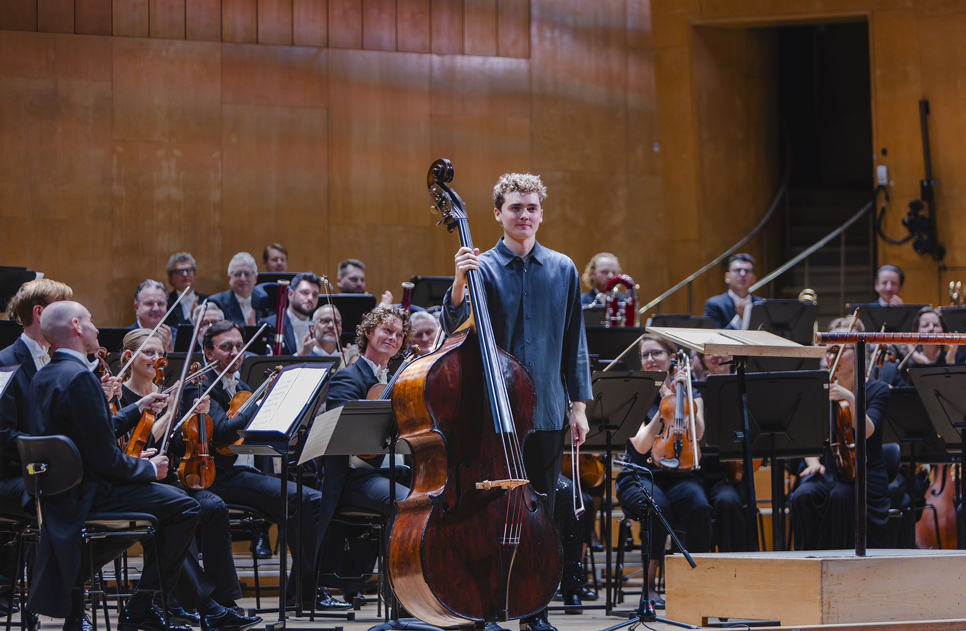 En man med en kontrabas står framför en orkester