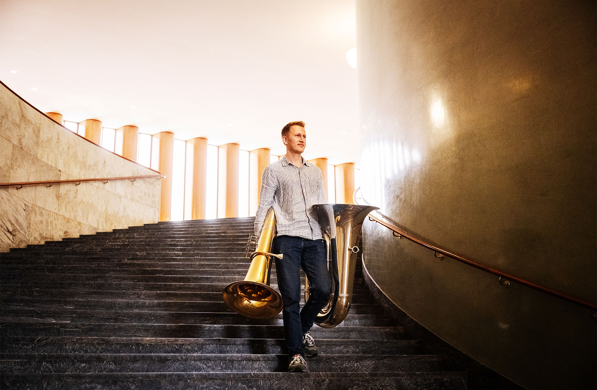 En ung man går ned för en trappa. Han bär på två tubor - en i varje hand.