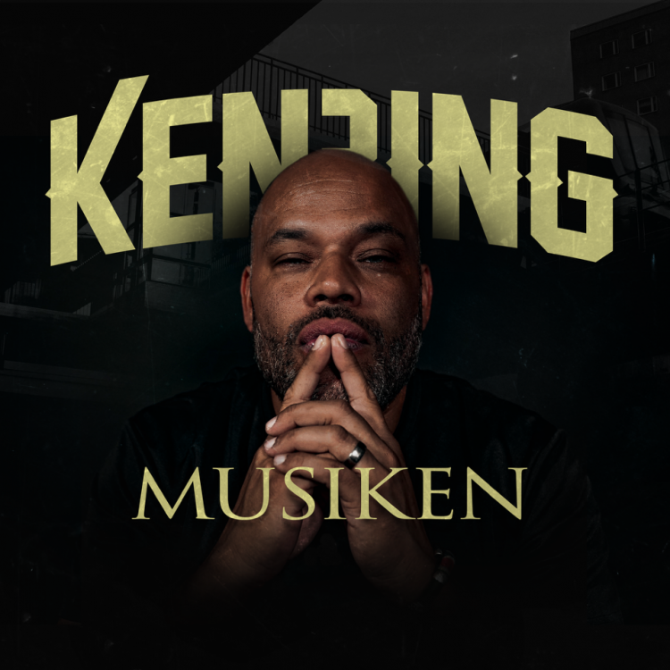 artisten Ken Ring sitter med fingertopparna mot varandra framför munnen. Svart bakgrund.