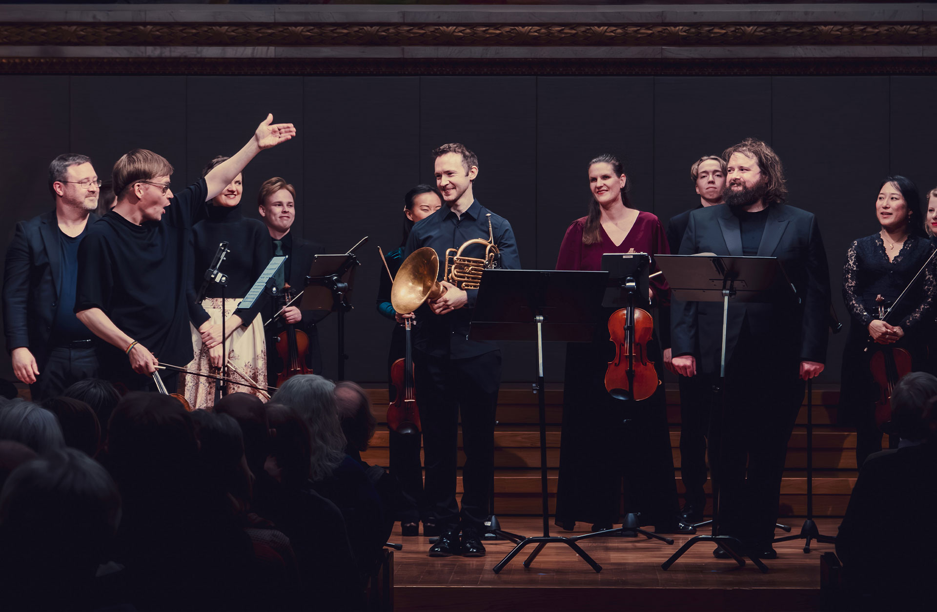 Applådtack efter en konsert där en ensemble står upp mot publiken och håller i sina instrument.