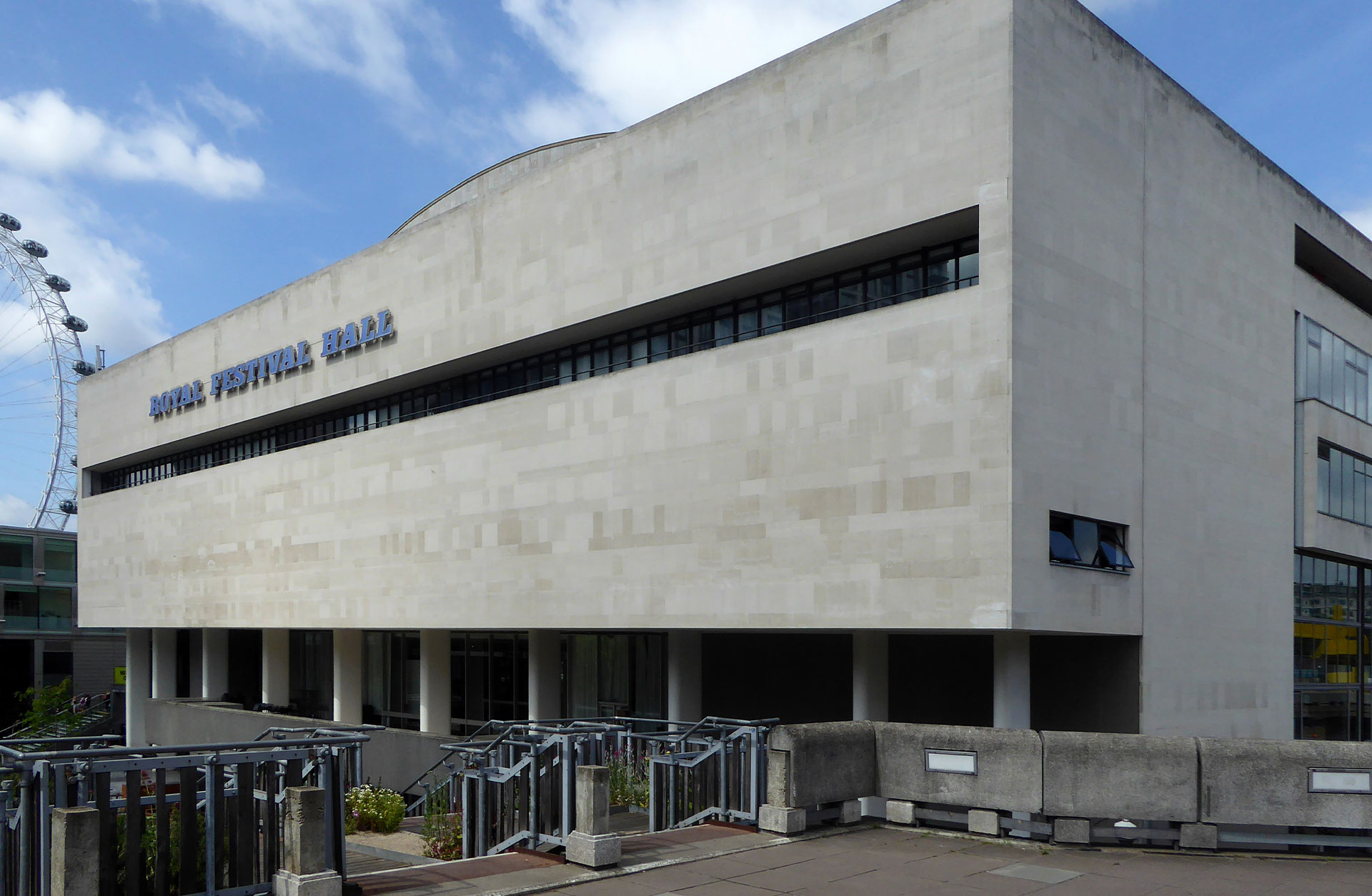 En fyrkantig grå byggnad med en rad med fönster längs hela sidan. En skylt med texten Royal Festival Hall är fäst på byggnaden.
