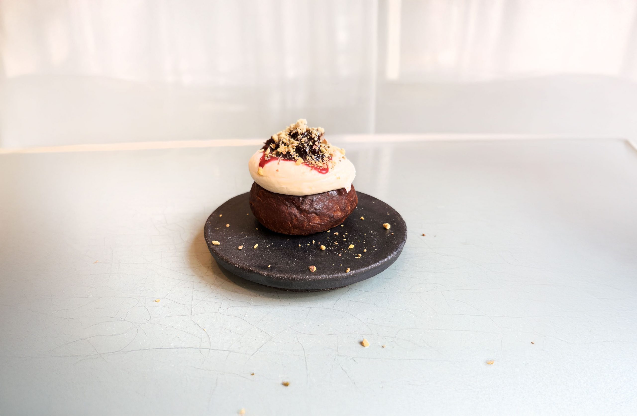 En bakelse på svart tallrik med smulor på bordet. Vit bakgrund.