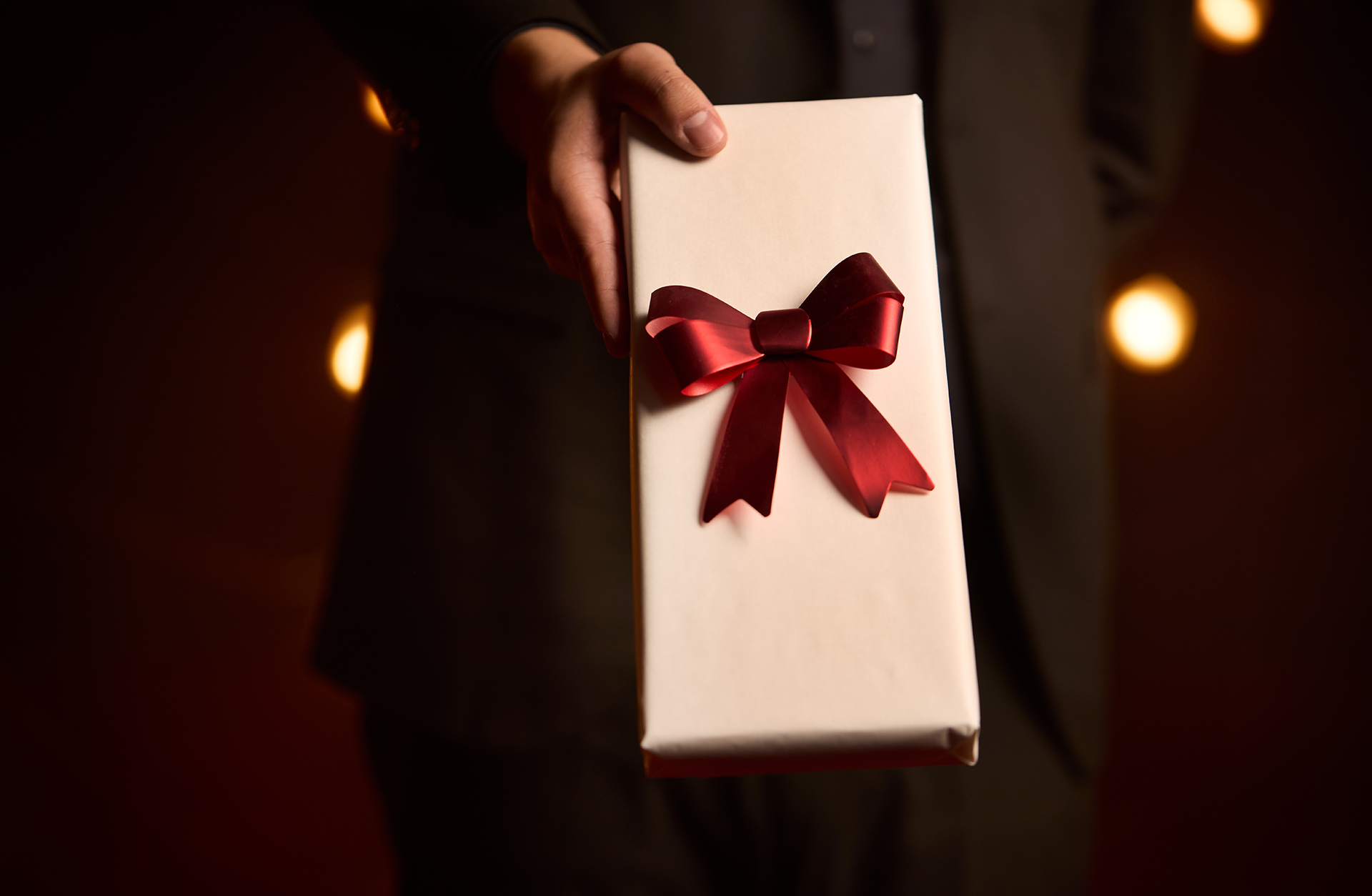 En man håller i ett vitt paket med en röd rosett