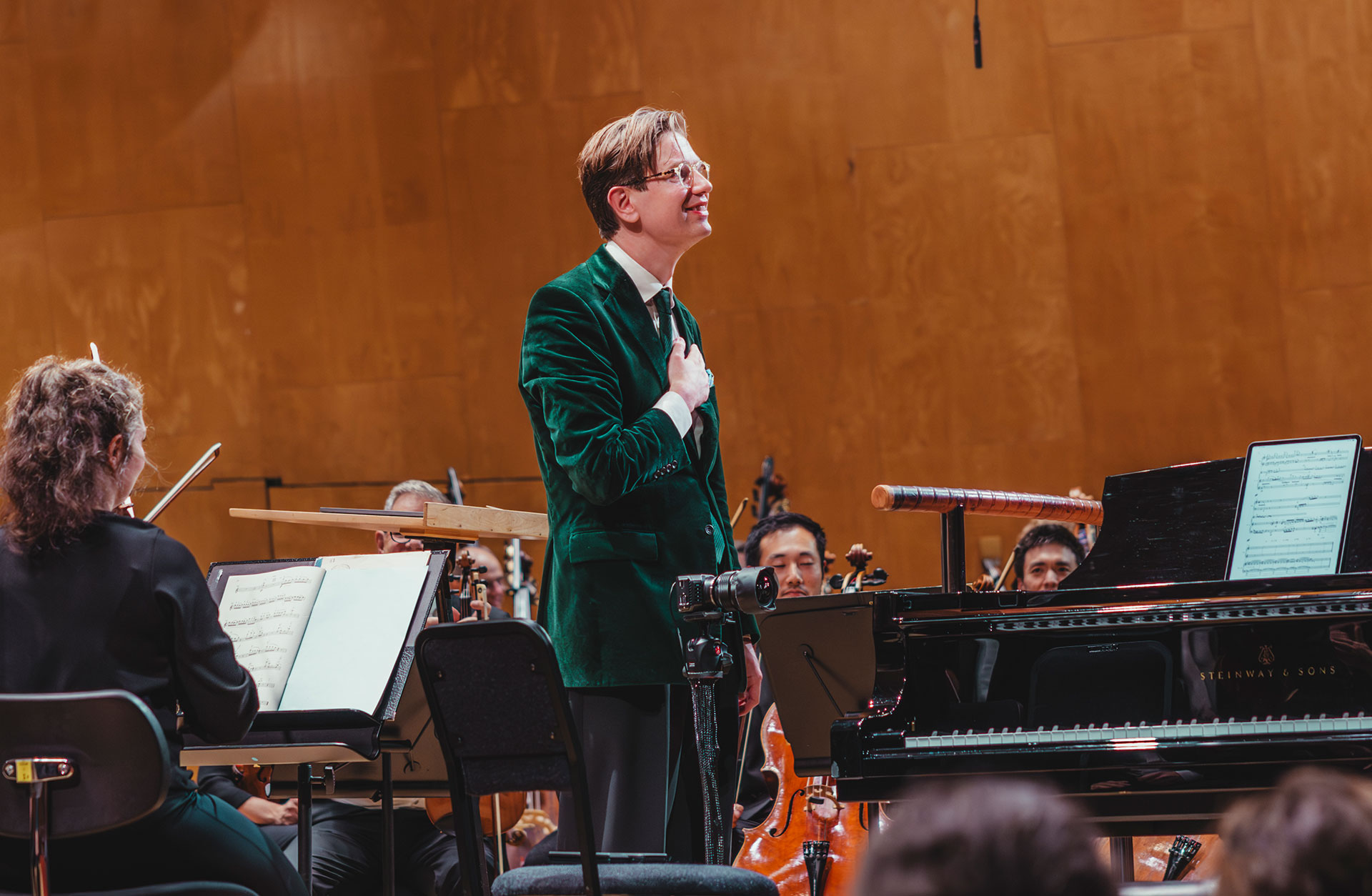 Pianisten Vikingur Olafsson vid flygeln efter avslutad konsert, med lyckligt leende mot publiken och handen på hjärtat.