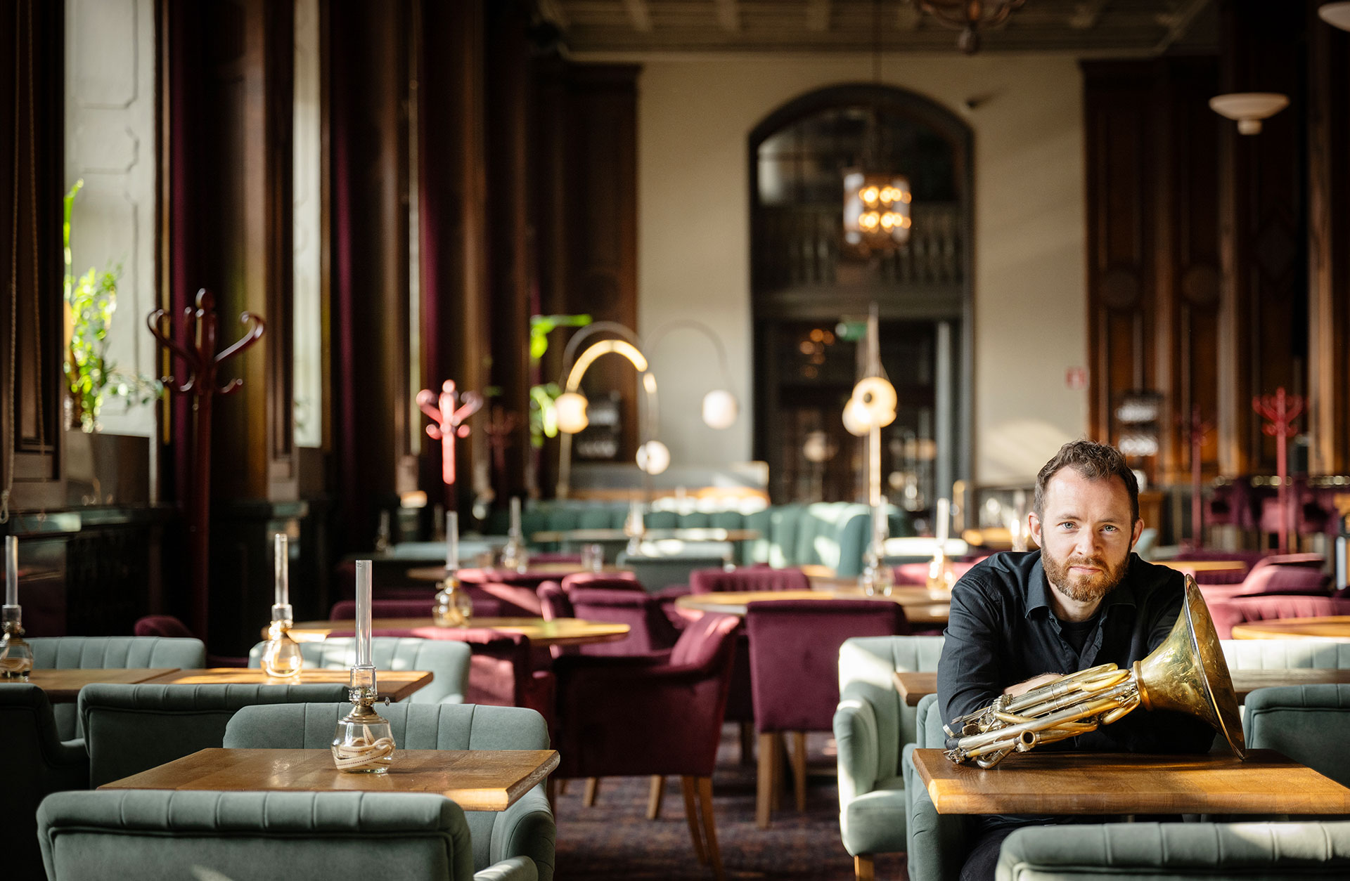En ung man sitter vid ett bord i en restaurang. På bordet ligger ett horn.